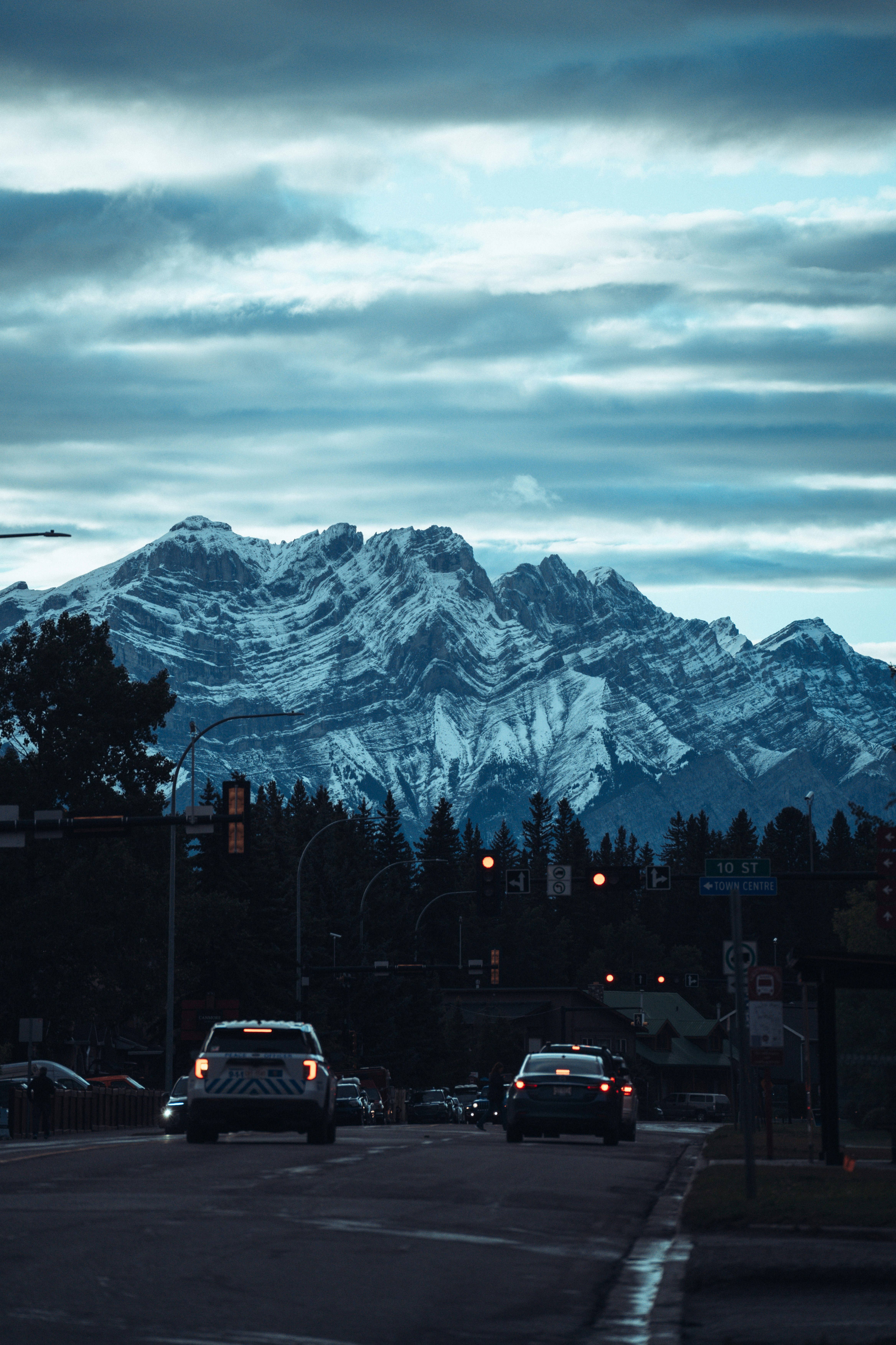 Cars are driving down the road in front of a mountain