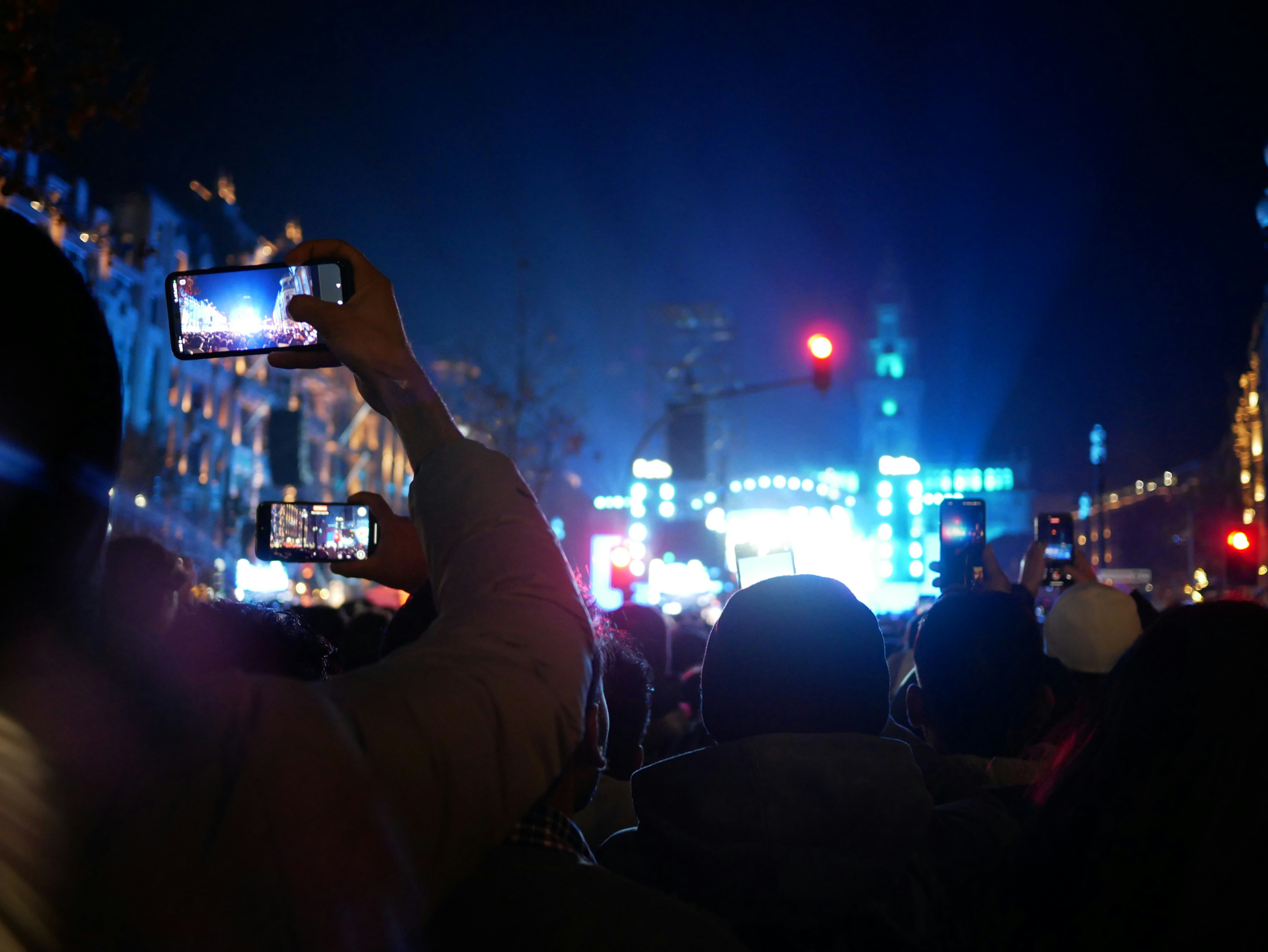 A split image showing on one side, a missile launch at night, and on the other, a group of people watching news on a mobile phone with worried expressions