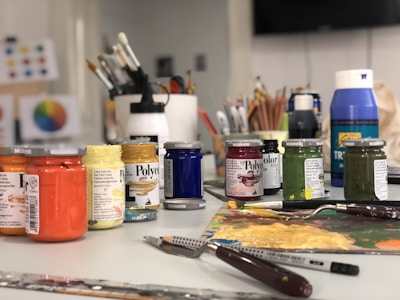 A white table topped with lots of paint and brushes