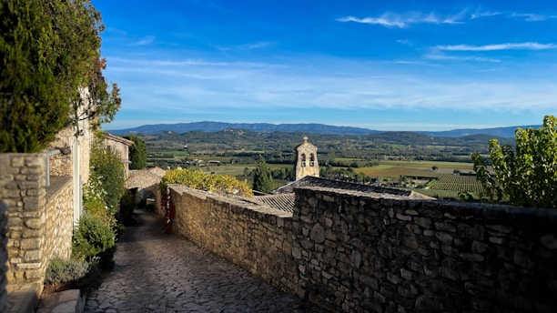 A stone wall with a clock tower in the distance