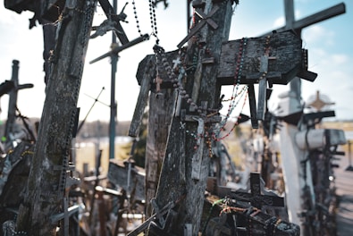 A bunch of wooden crosses hanging from the side of a road