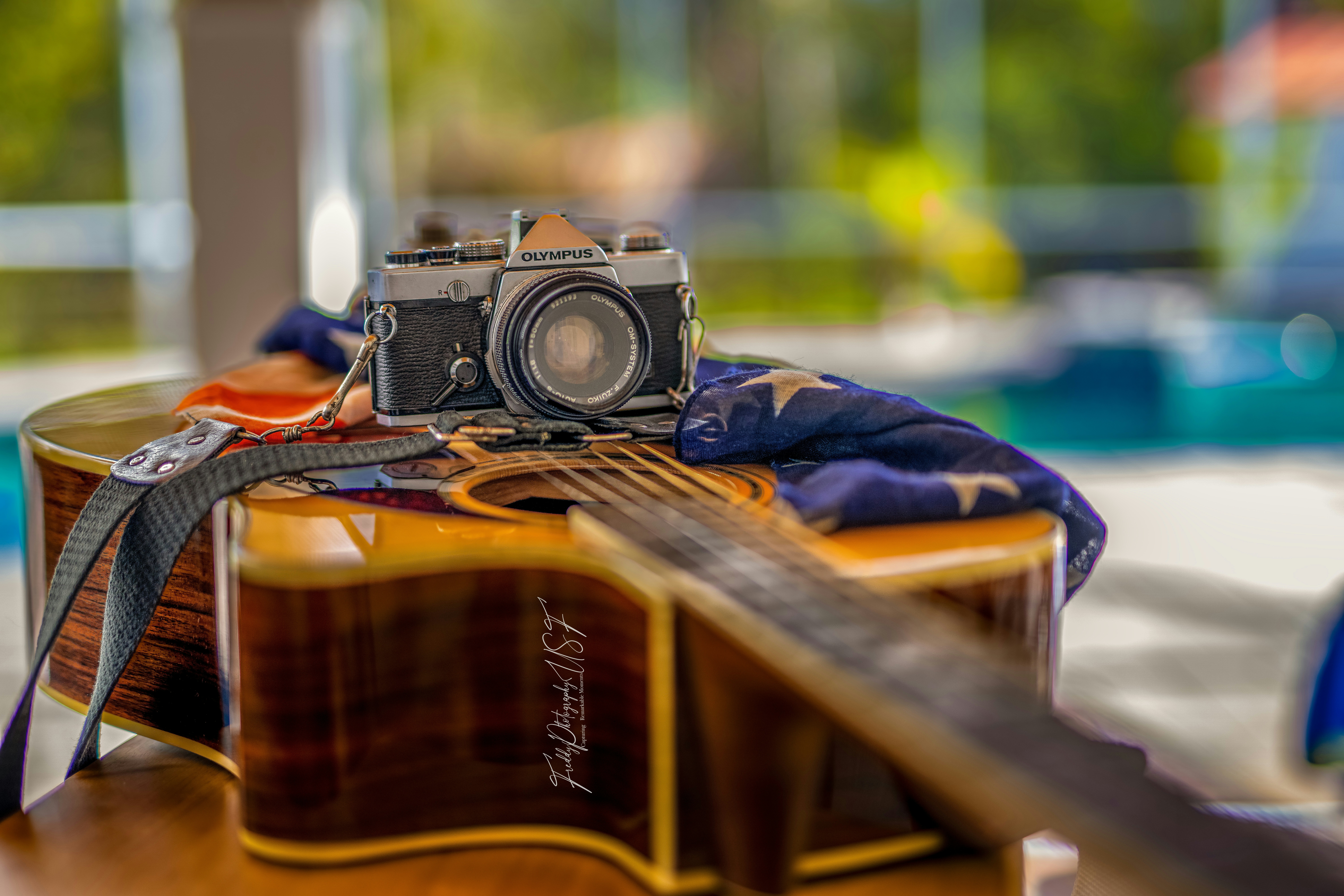 Une caméra posée sur une table en bois à côté d’une guitare