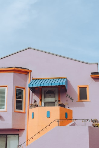 A pink house with a blue awning