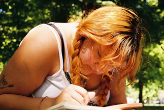 Une femme écrit dans un livre dans le parc