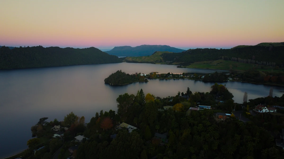 Lake Ōkareka near Rotorua at dusk, with forested hills and a flat-topped mountain on the skyline