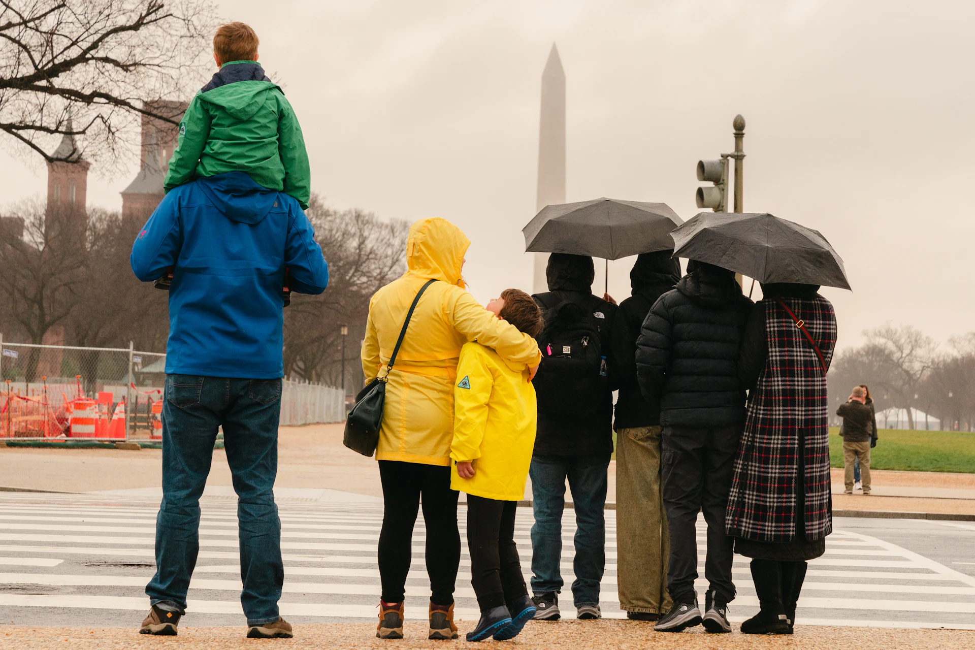 A group of people standing in the rain with umbrellas