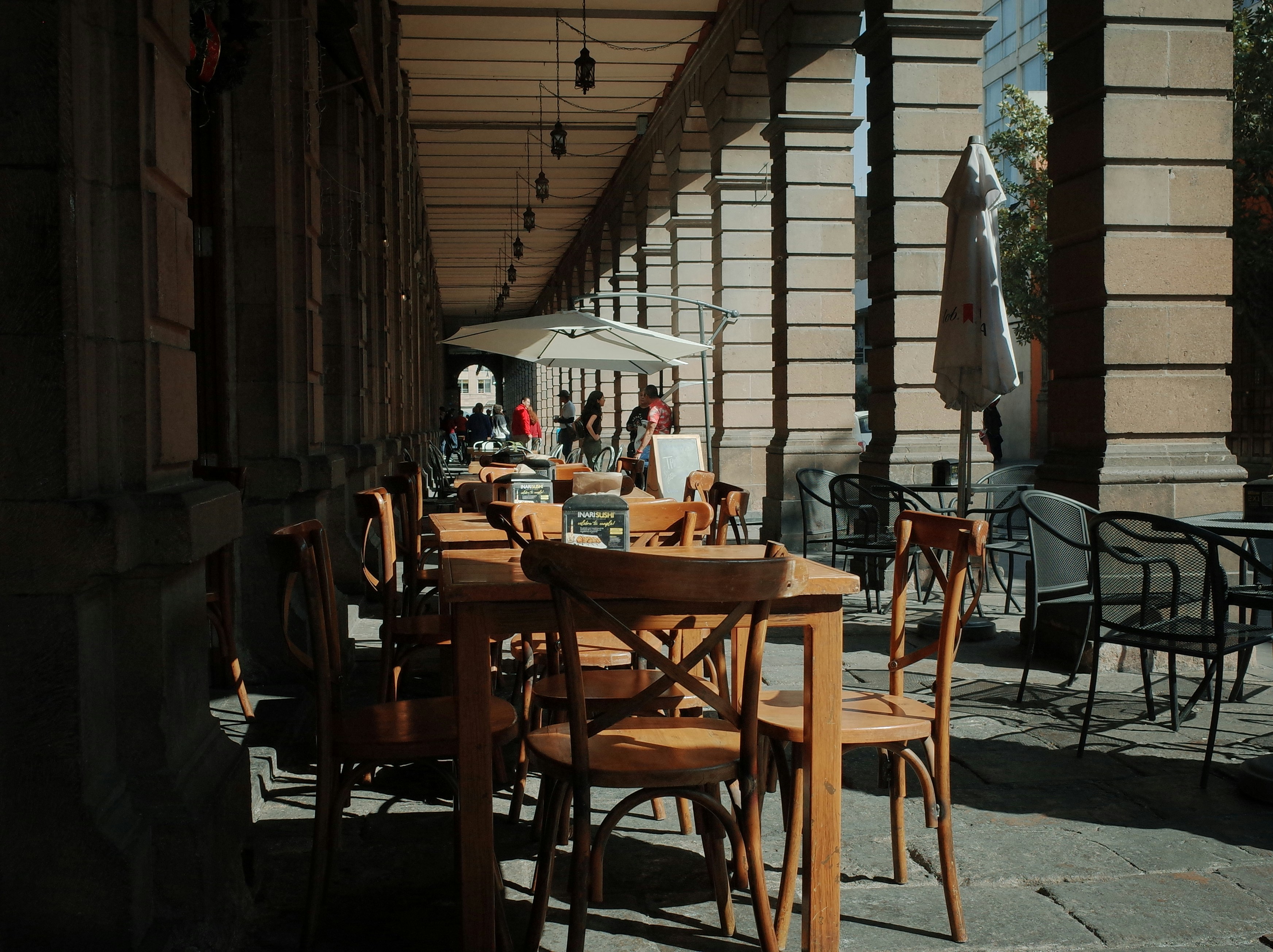 A group of wooden tables and chairs on a sidewalk
