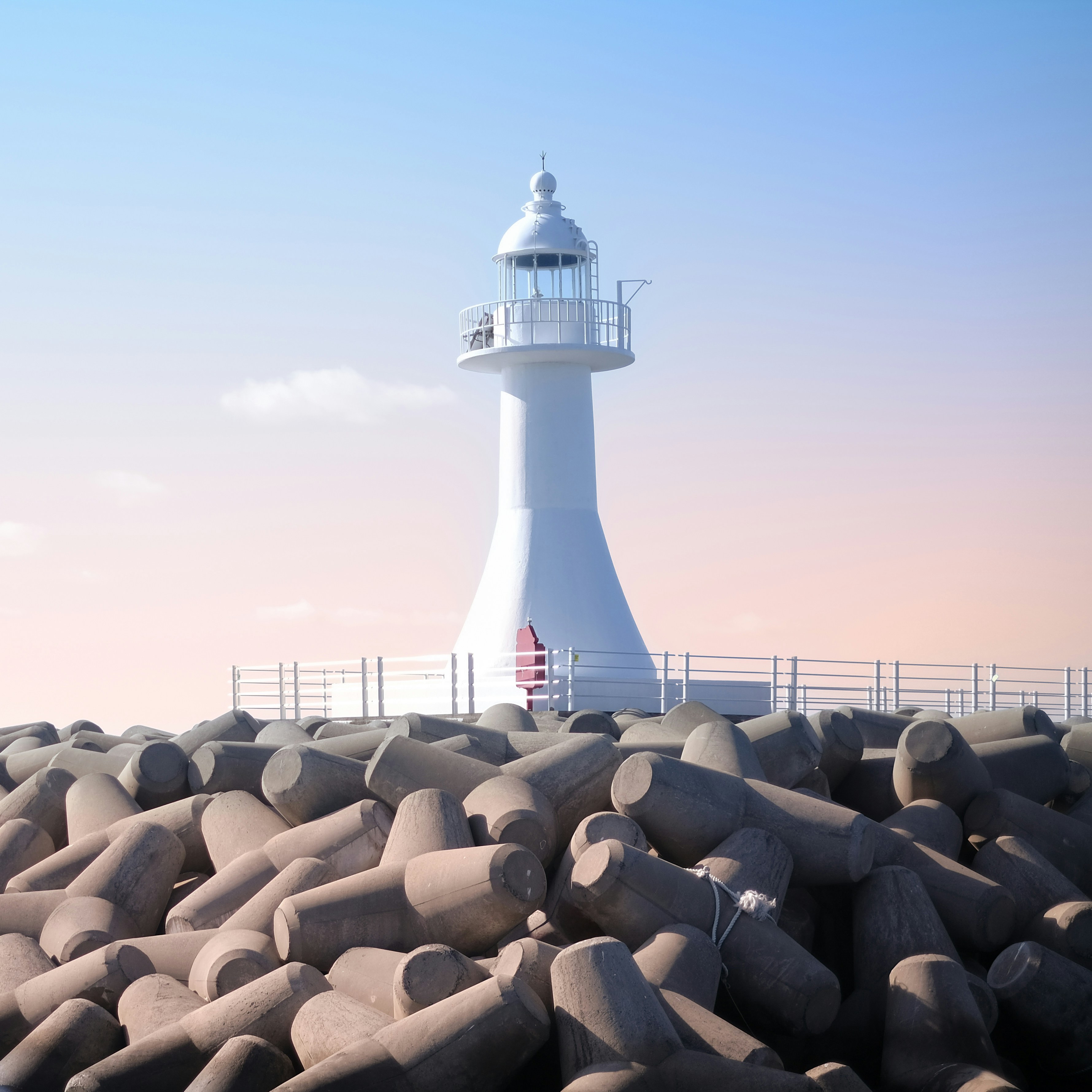 A white lighthouse sitting on top of a rocky beach
