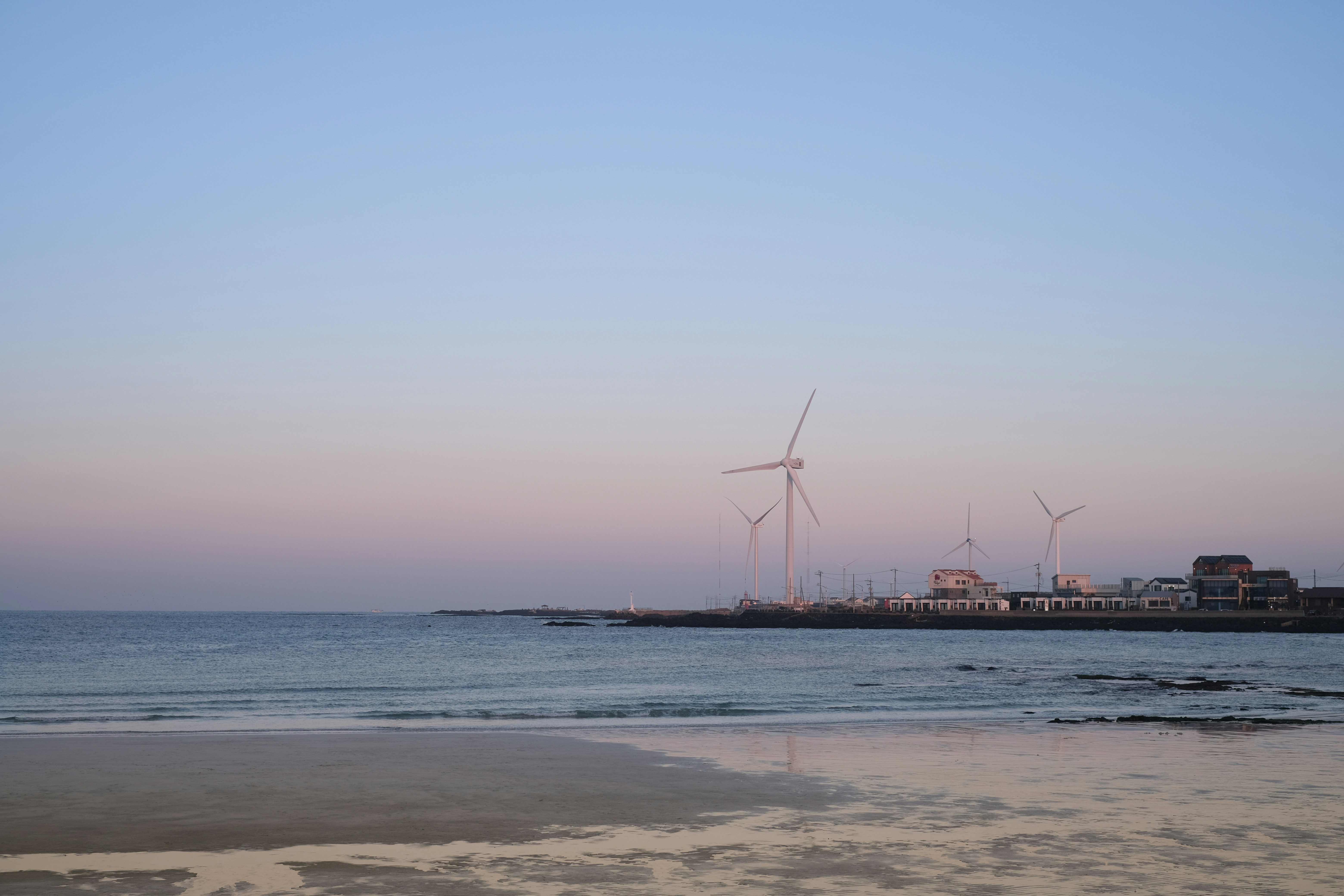 Une plage avec quelques moulins à vent au loin