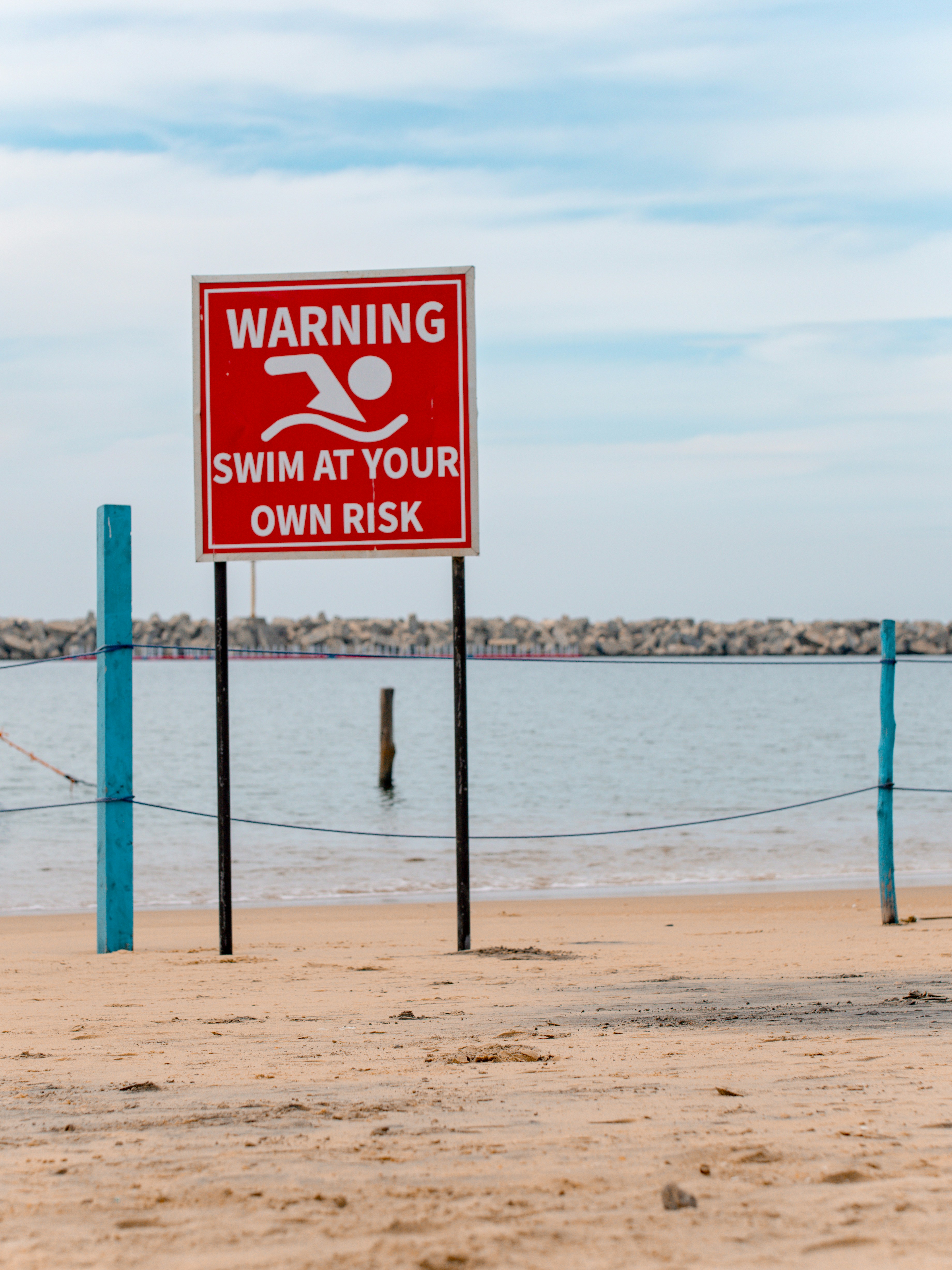 A warning sign on a beach next to a body of water