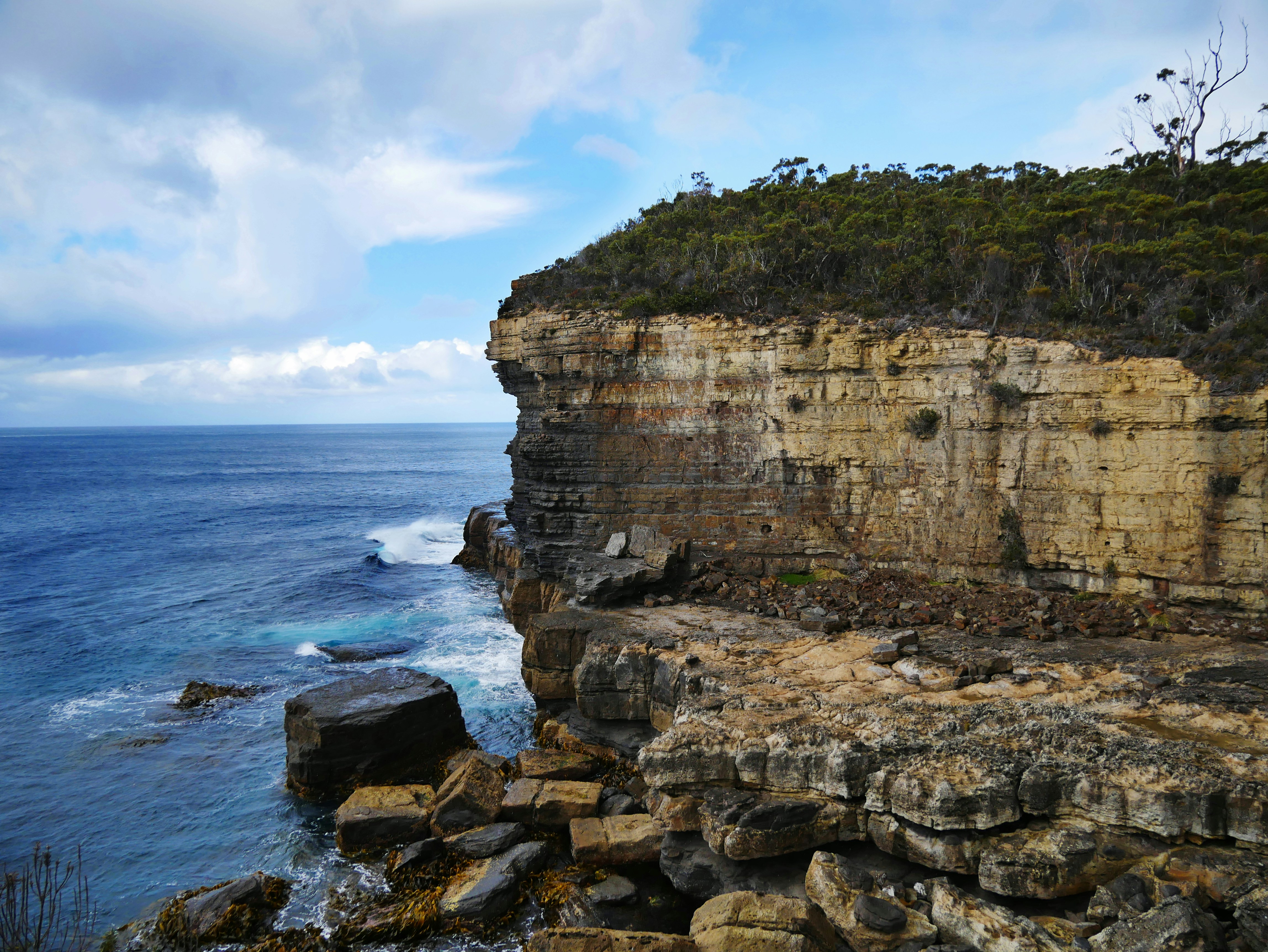 Светлый прибрежный утёс и каменистая кромка моря.