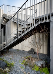 A spiral staircase next to a building with moss growing on the ground