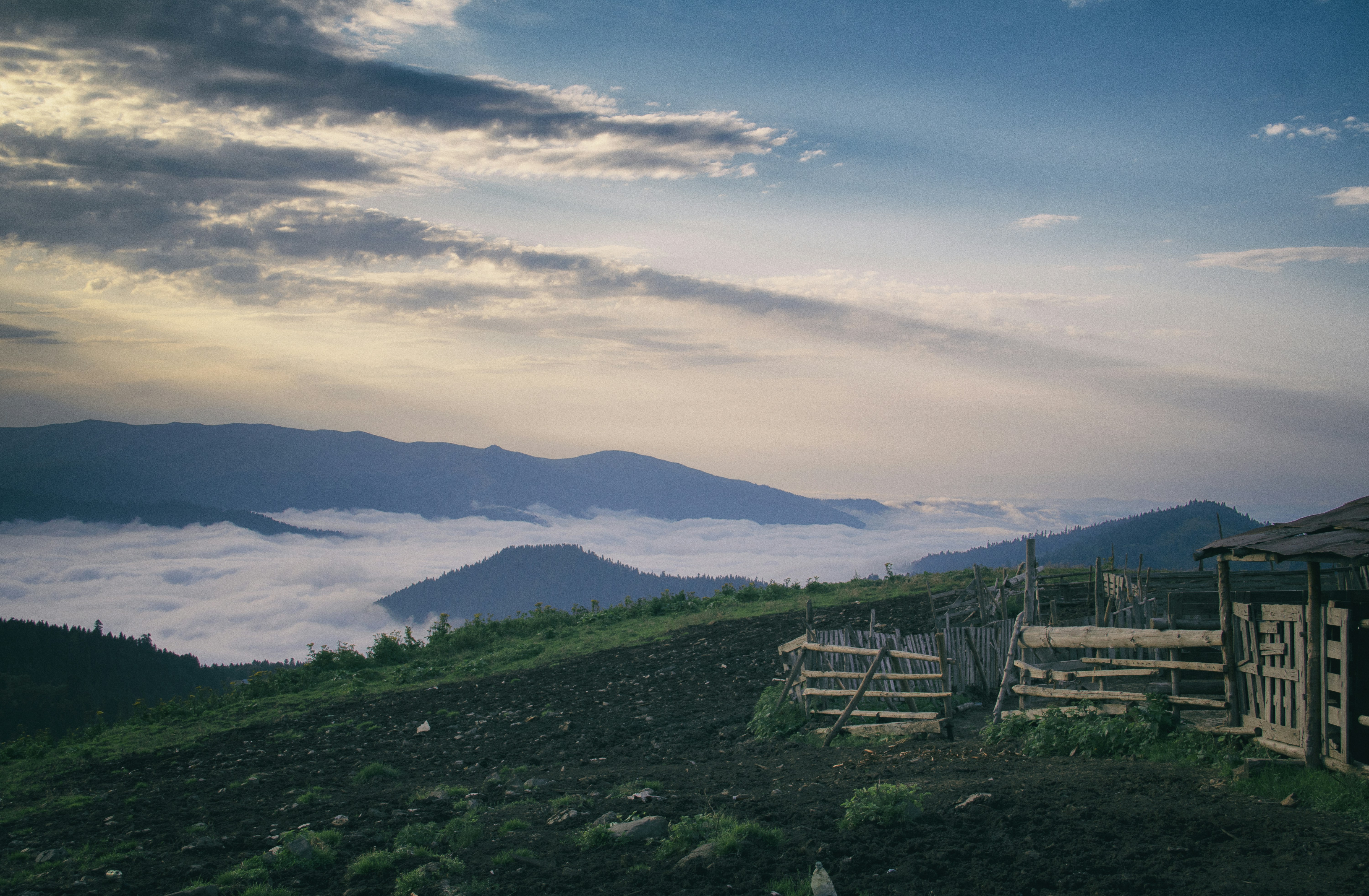 A wooden fence on a grassy hill with mountains in the background, Zekari Pass is a scenic mountain pass in Georgia, offering breathtaking views of valleys, peaks, and alpine meadows. Perfect for nature lovers and adventurers.