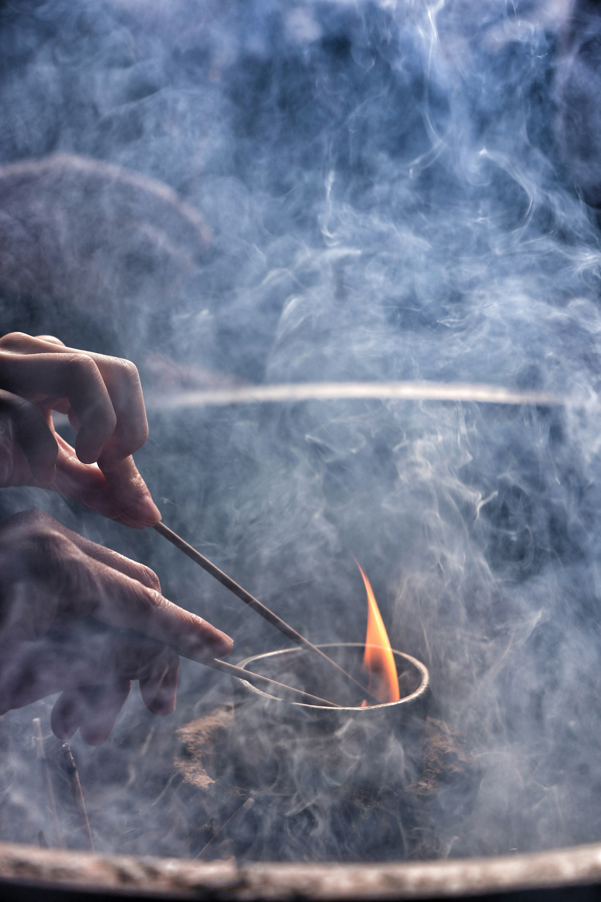 A person holding a spoon over a fire in a pot