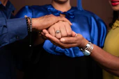 A man and woman holding hands in front of a brown background