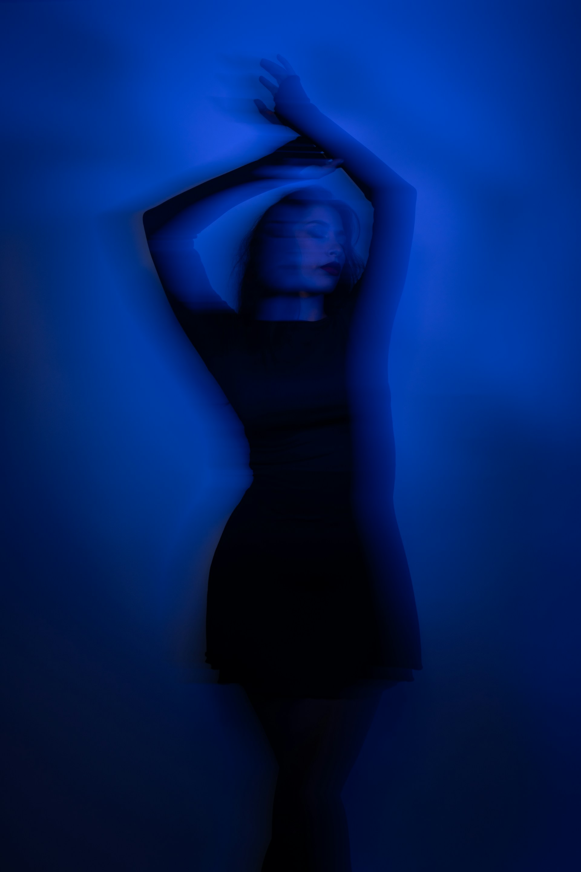 A woman in a black dress standing in a blue room