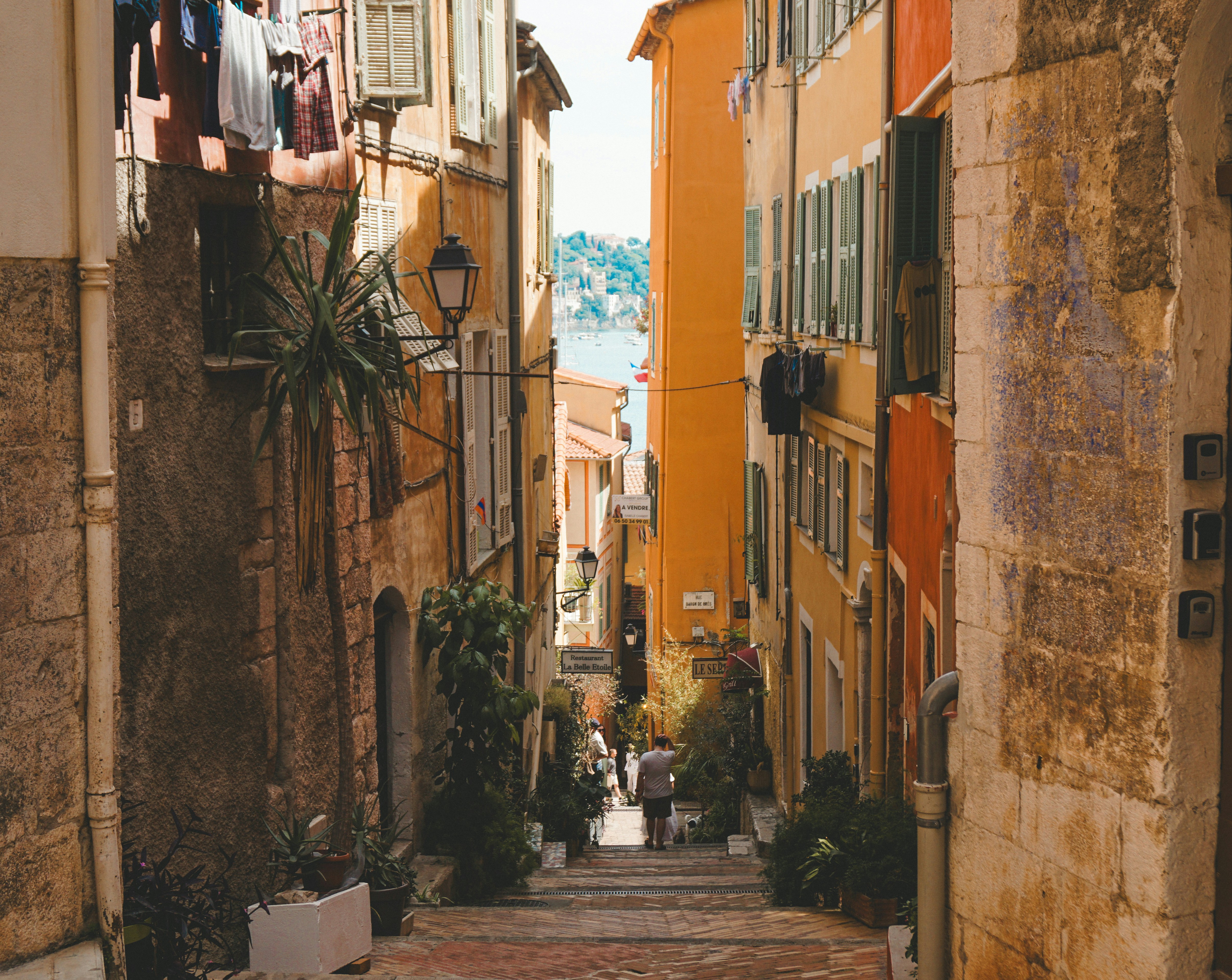 A narrow street with a few people walking down it