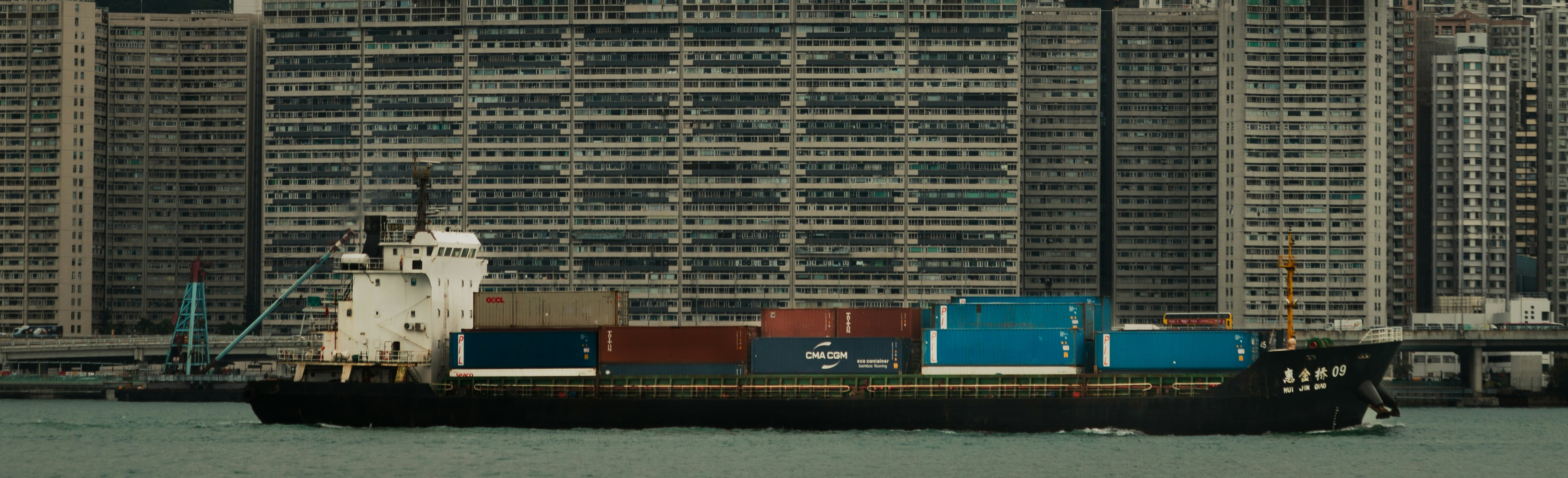 A large boat floating in a body of water near tall buildings