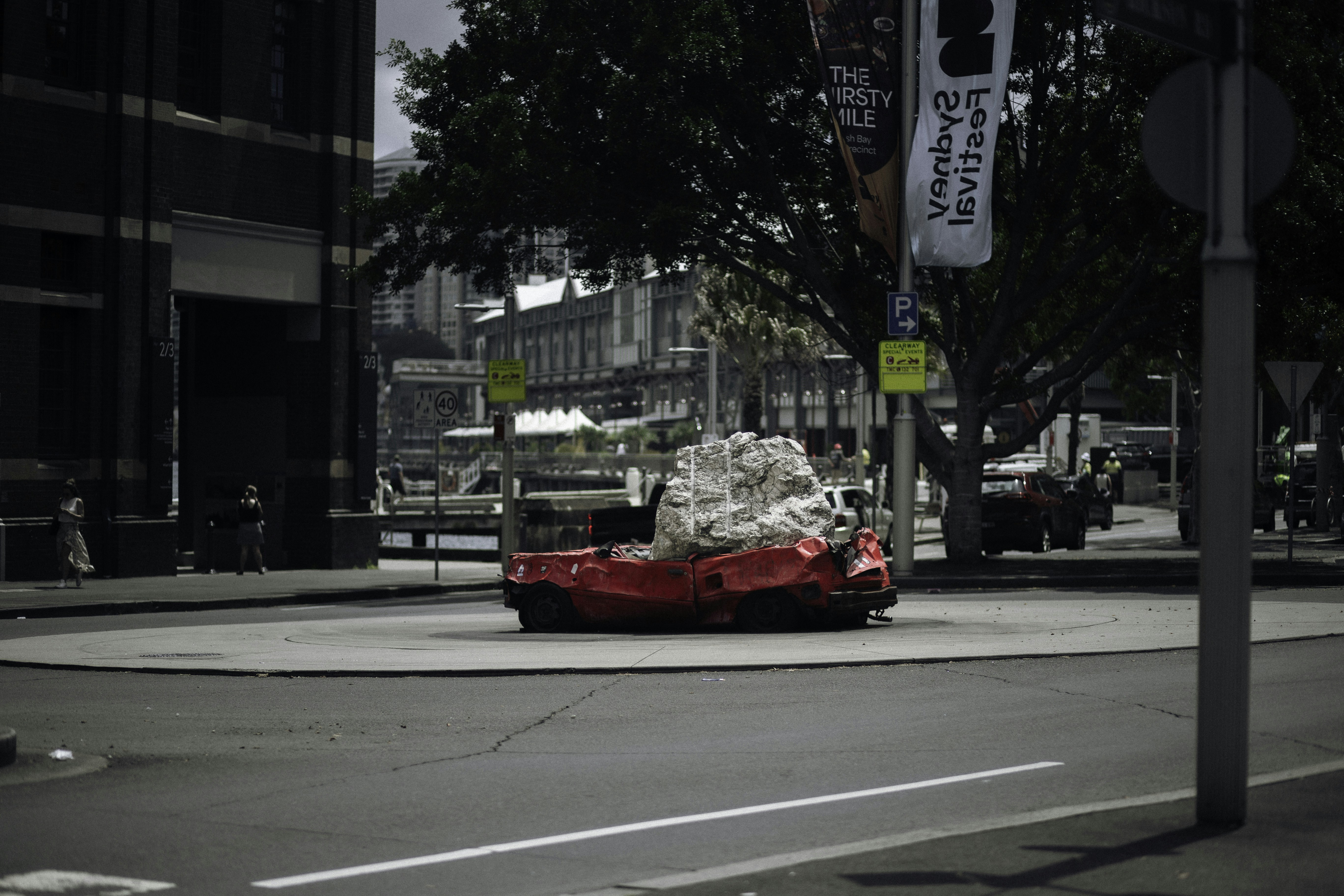 A red car driving down a street next to tall buildings photo – Free ...