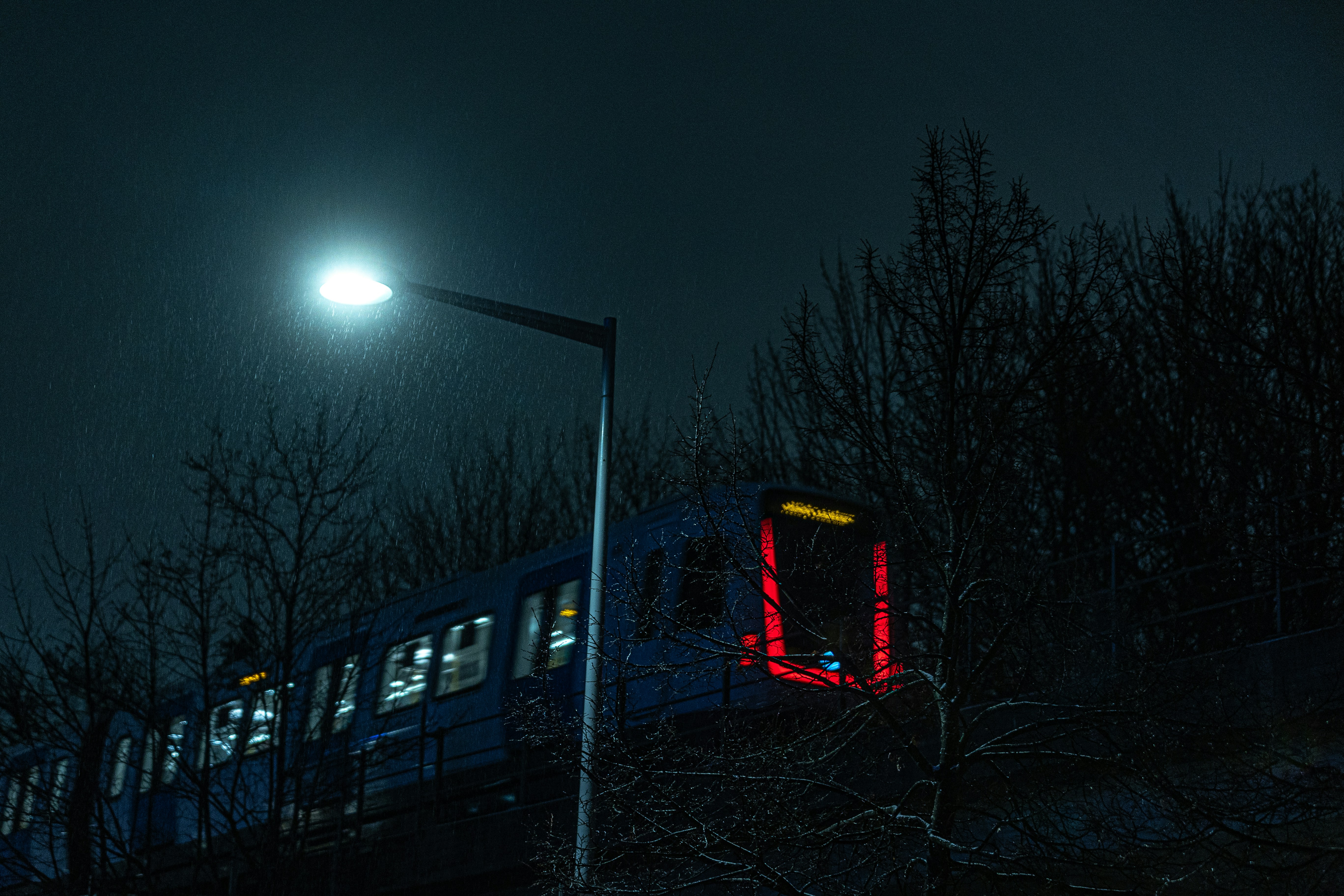 A blue train traveling down train tracks at night