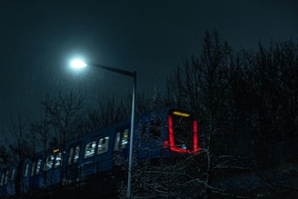 A blue train traveling down train tracks at night