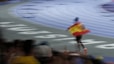 A man holding a spanish flag on top of a race track