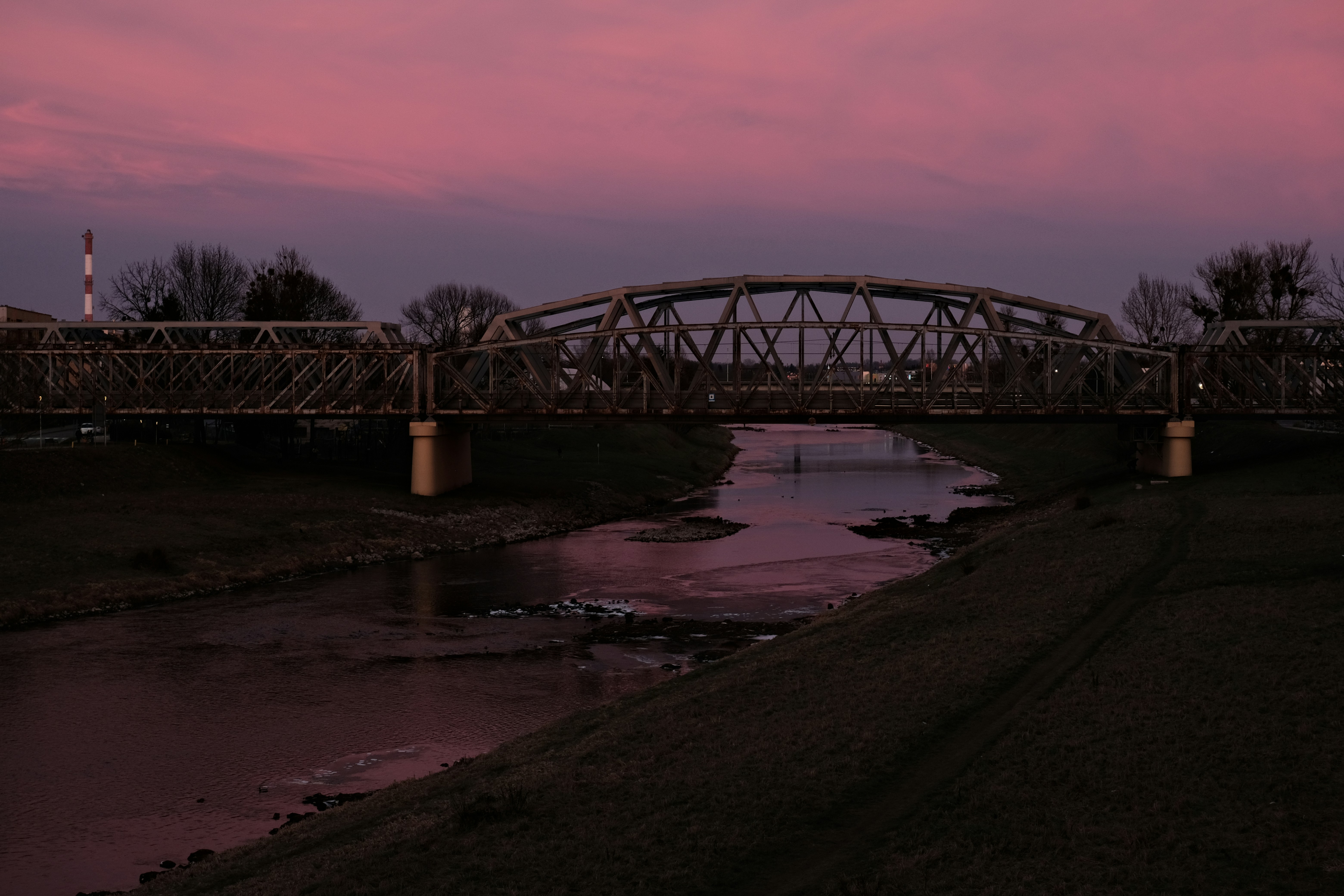 A bridge over a river with a pink sky in the background