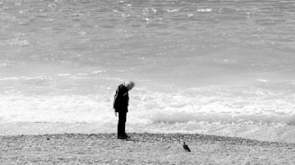 A man standing on a beach next to the ocean