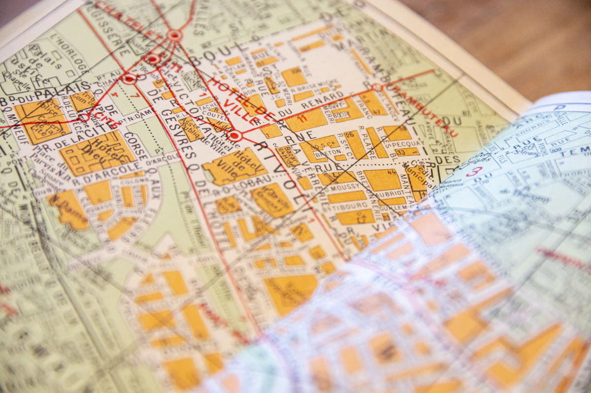 Gros plan d'un plan de ville en papier posé sur une table en bois, rues et places nommées en français