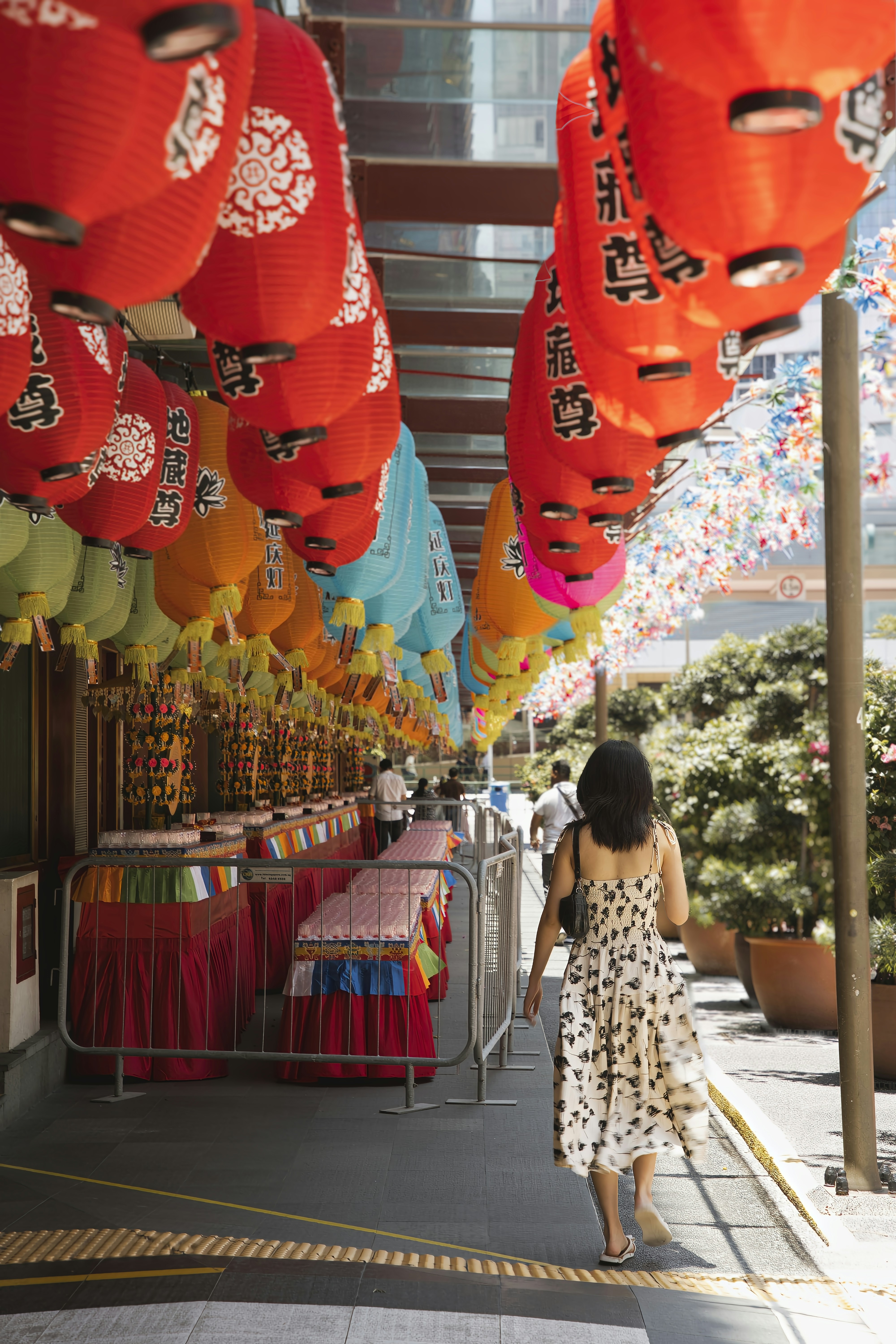 A woman walking down a street under lots of lanterns