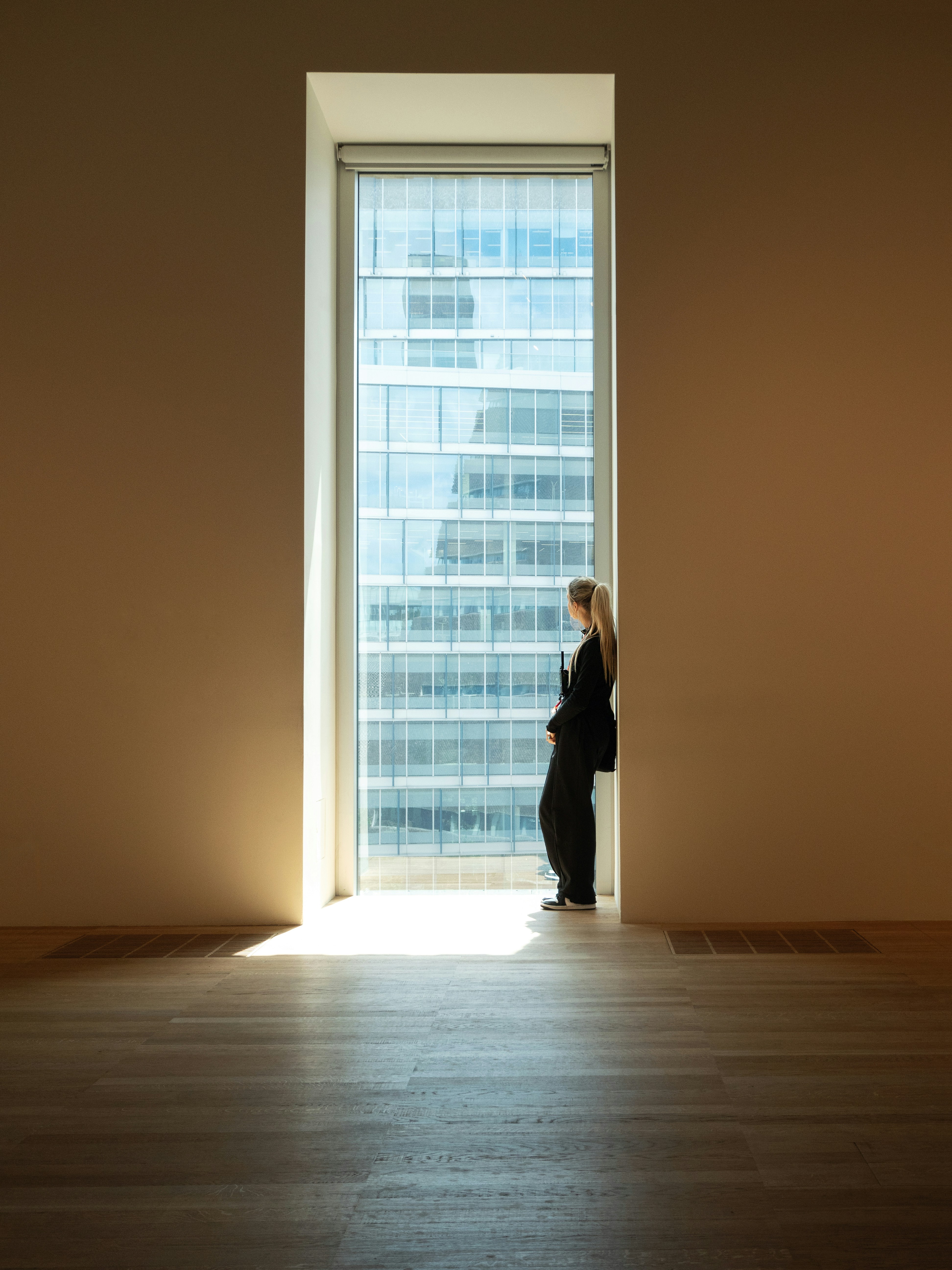Eine Frau, die in einem leeren Raum vor einem Fenster steht