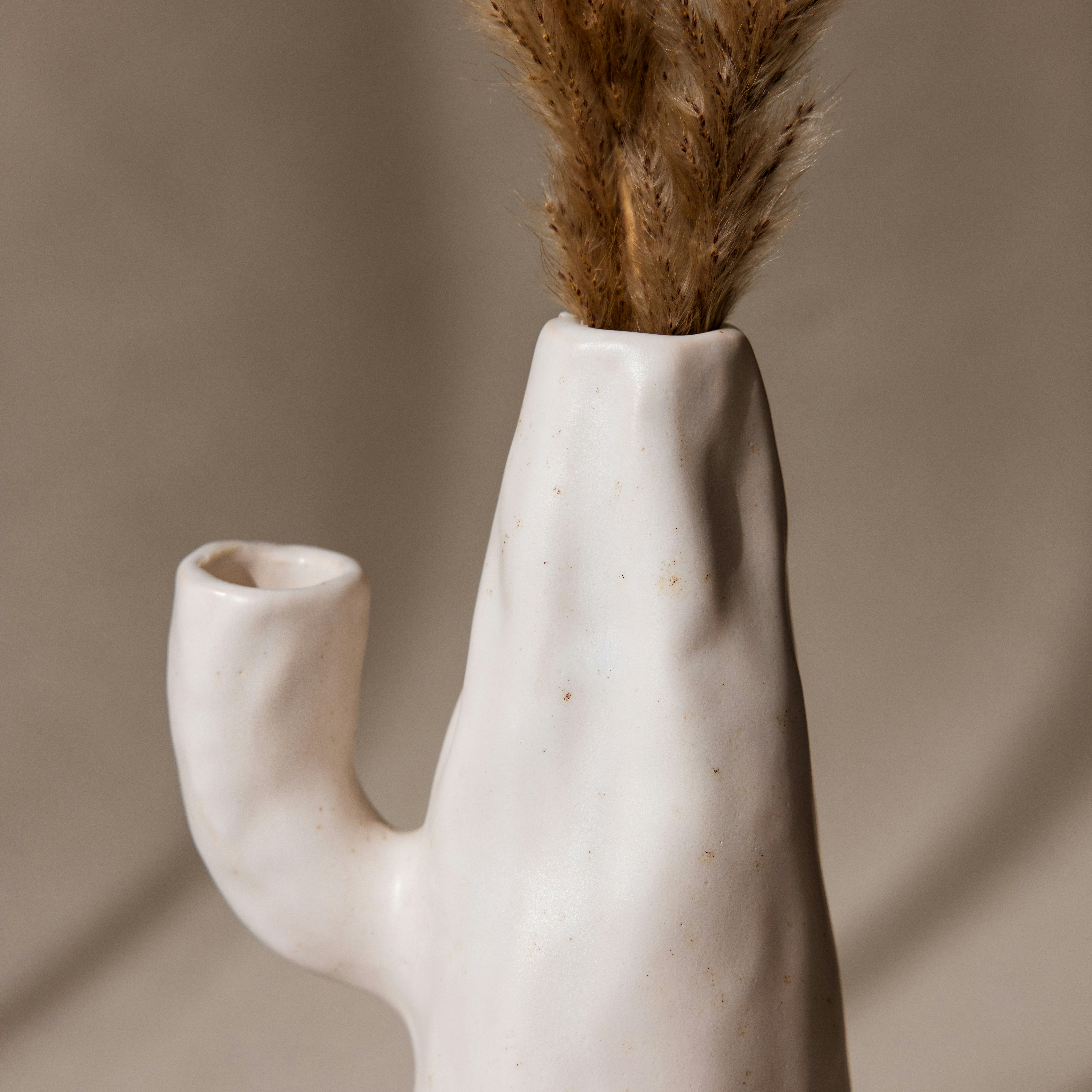 A white vase with a plant sticking out of it