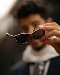 A close up of a person holding a pair of sunglasses