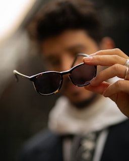 A close up of a person holding a pair of sunglasses