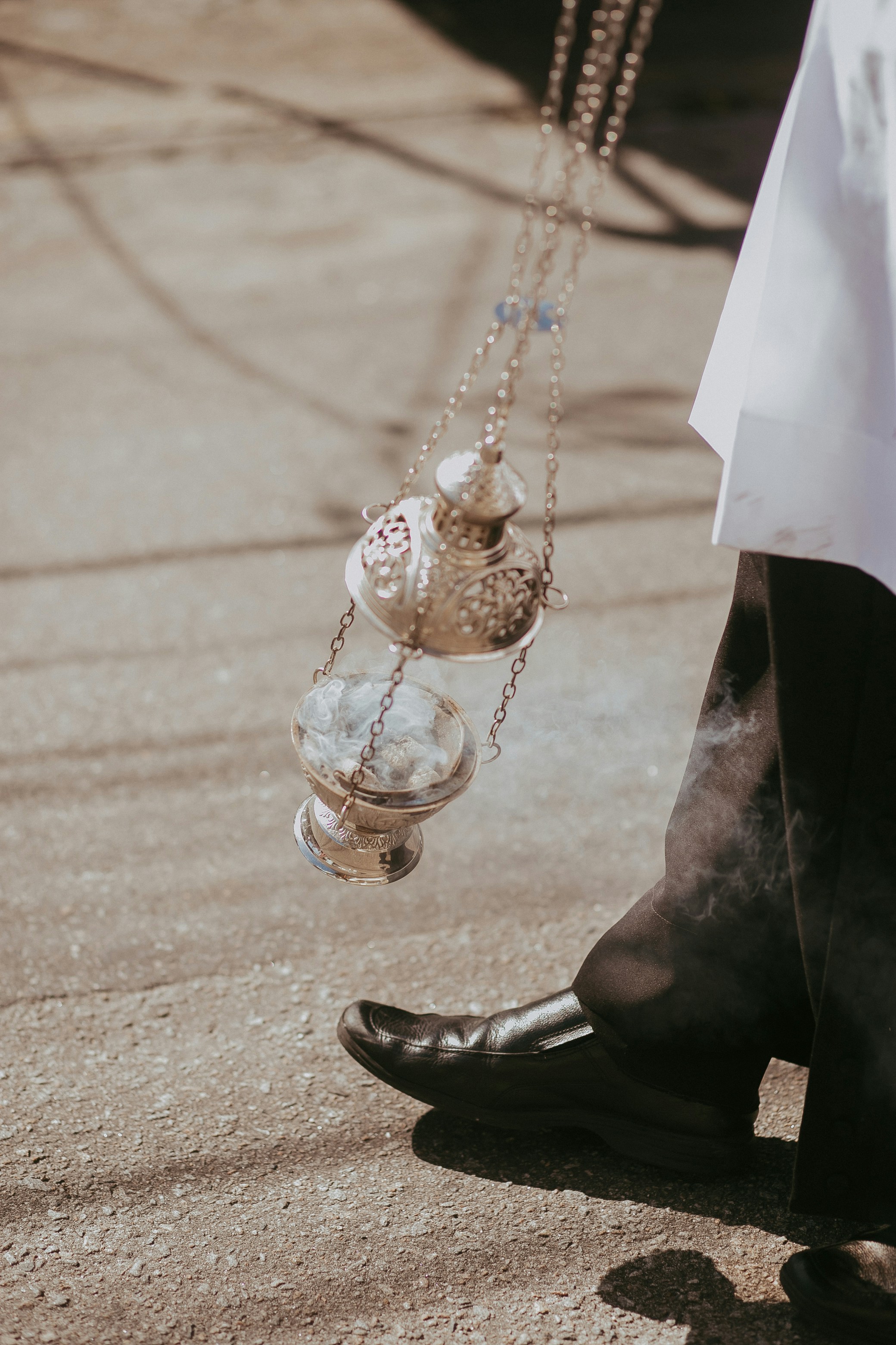 Un hombre con camisa blanca y pantalones negros sosteniendo un rosario