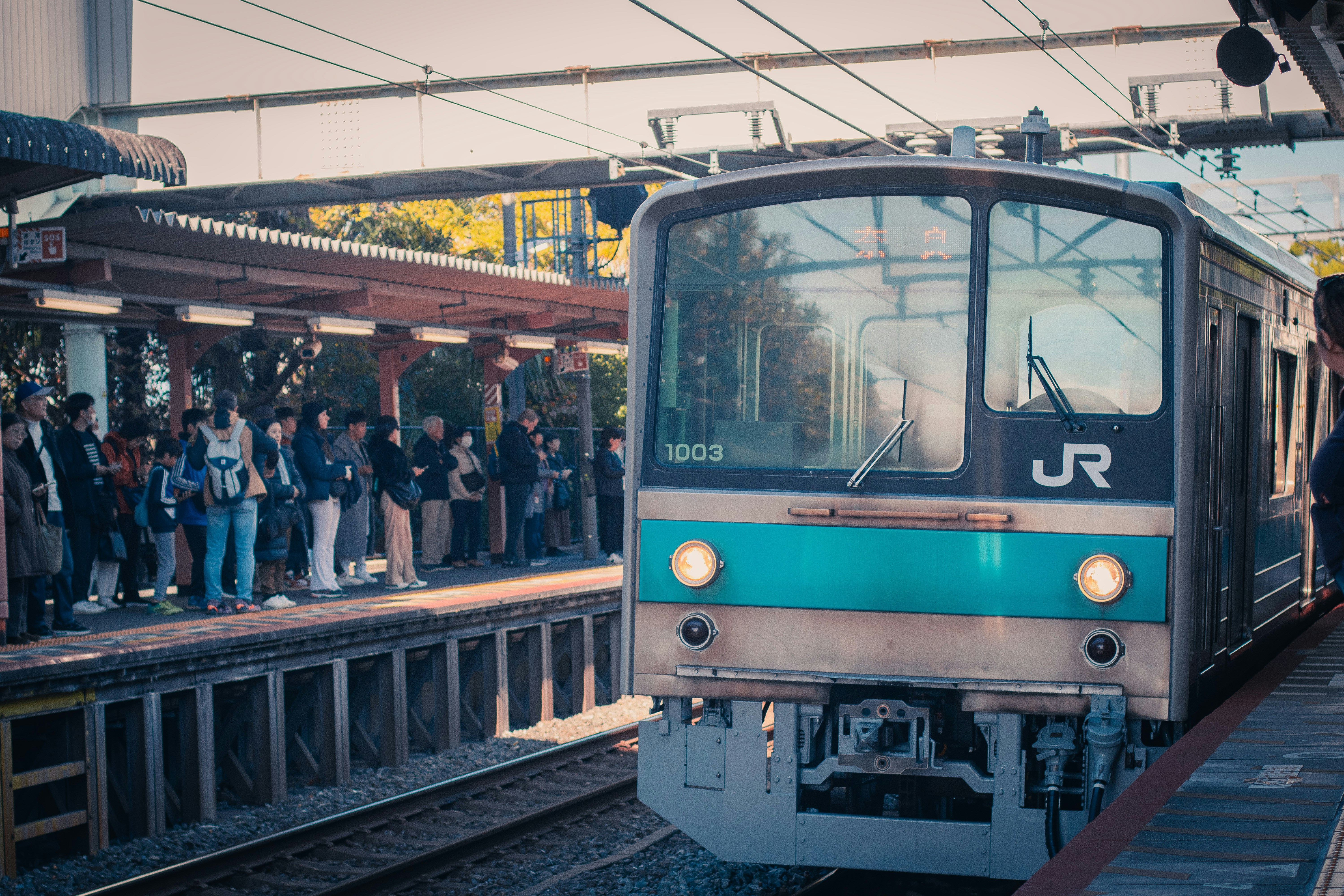 Un train qui s’arrête dans une gare à côté d’une foule de personnes