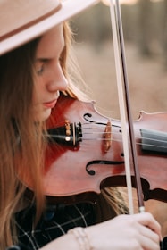 A woman in a hat playing a violin