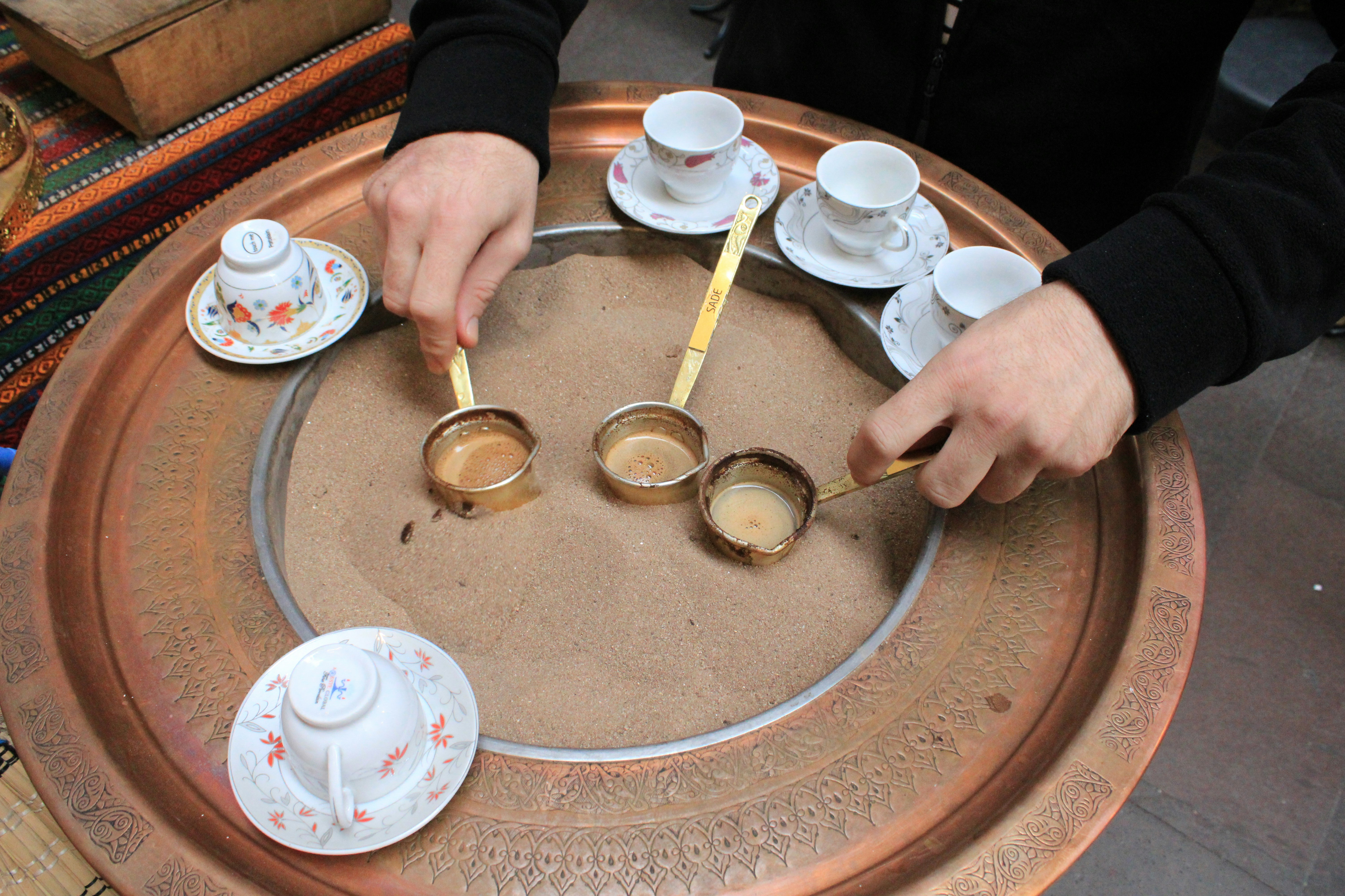 A person sitting at a table with cups and saucers