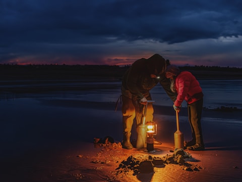 A couple of people standing on top of a sandy beach