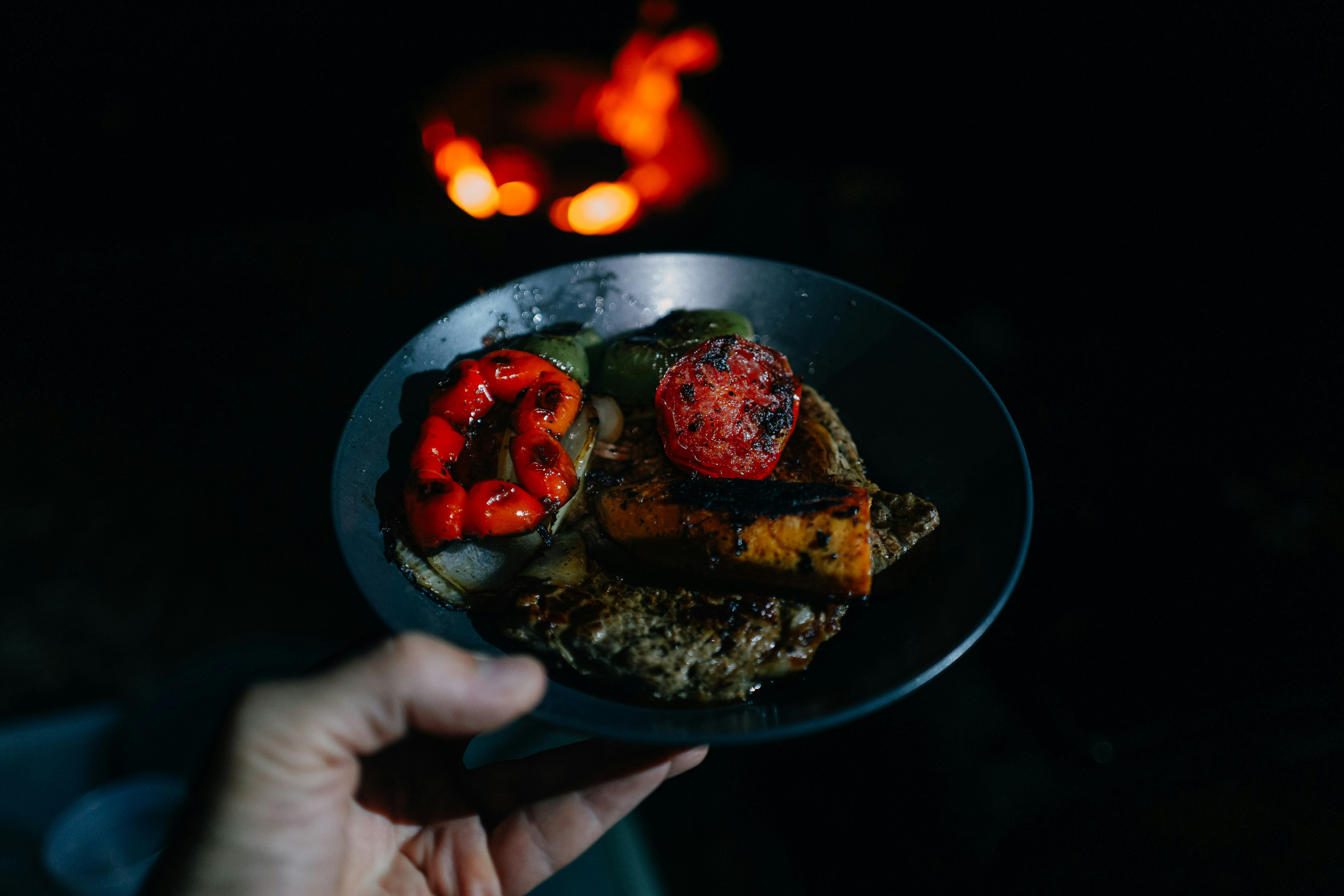 Eine Person, die im Dunkeln einen Teller mit Essen hält