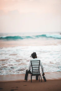 A person sitting on a chair on the beach