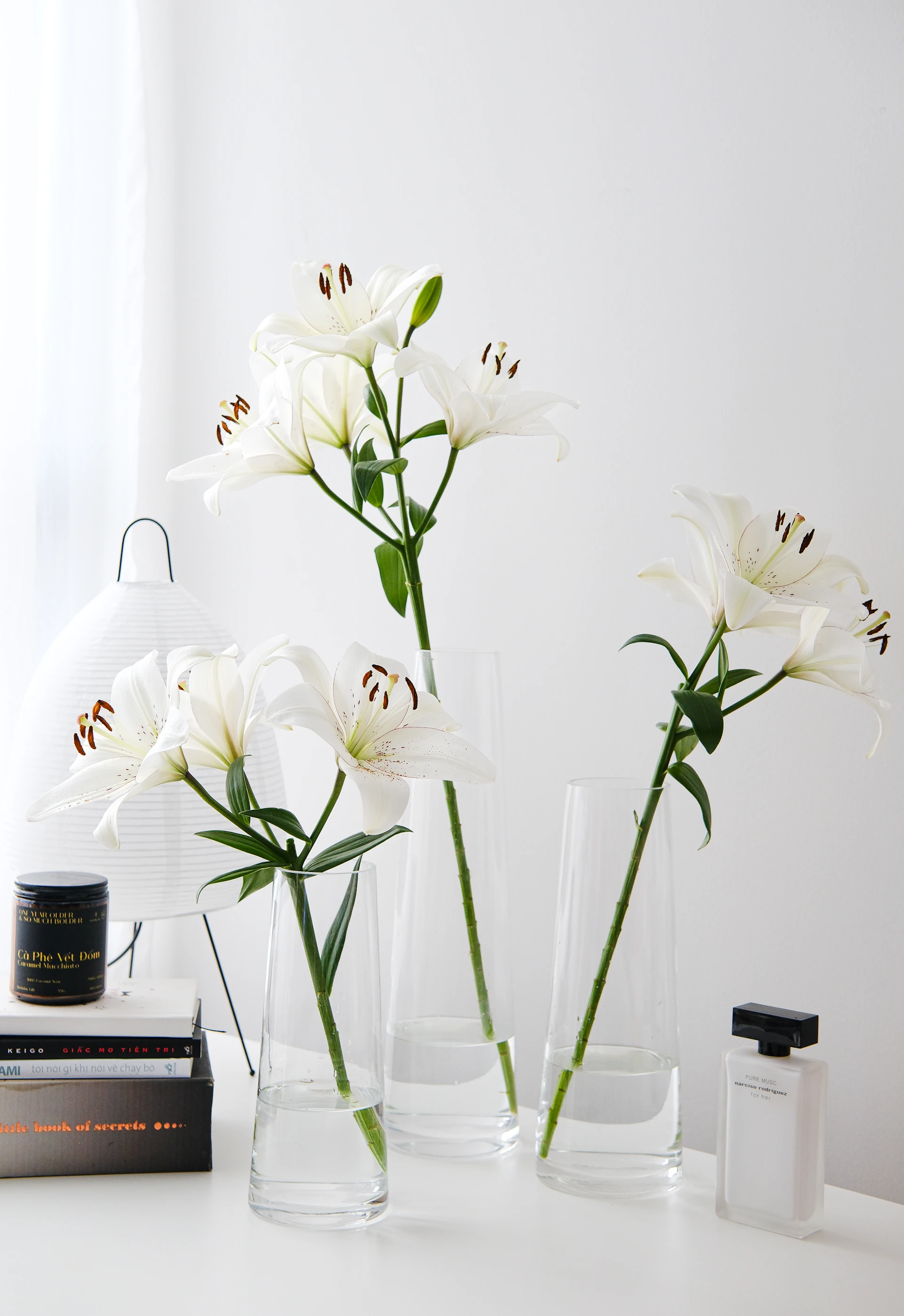 A white table topped with three vases filled with flowers