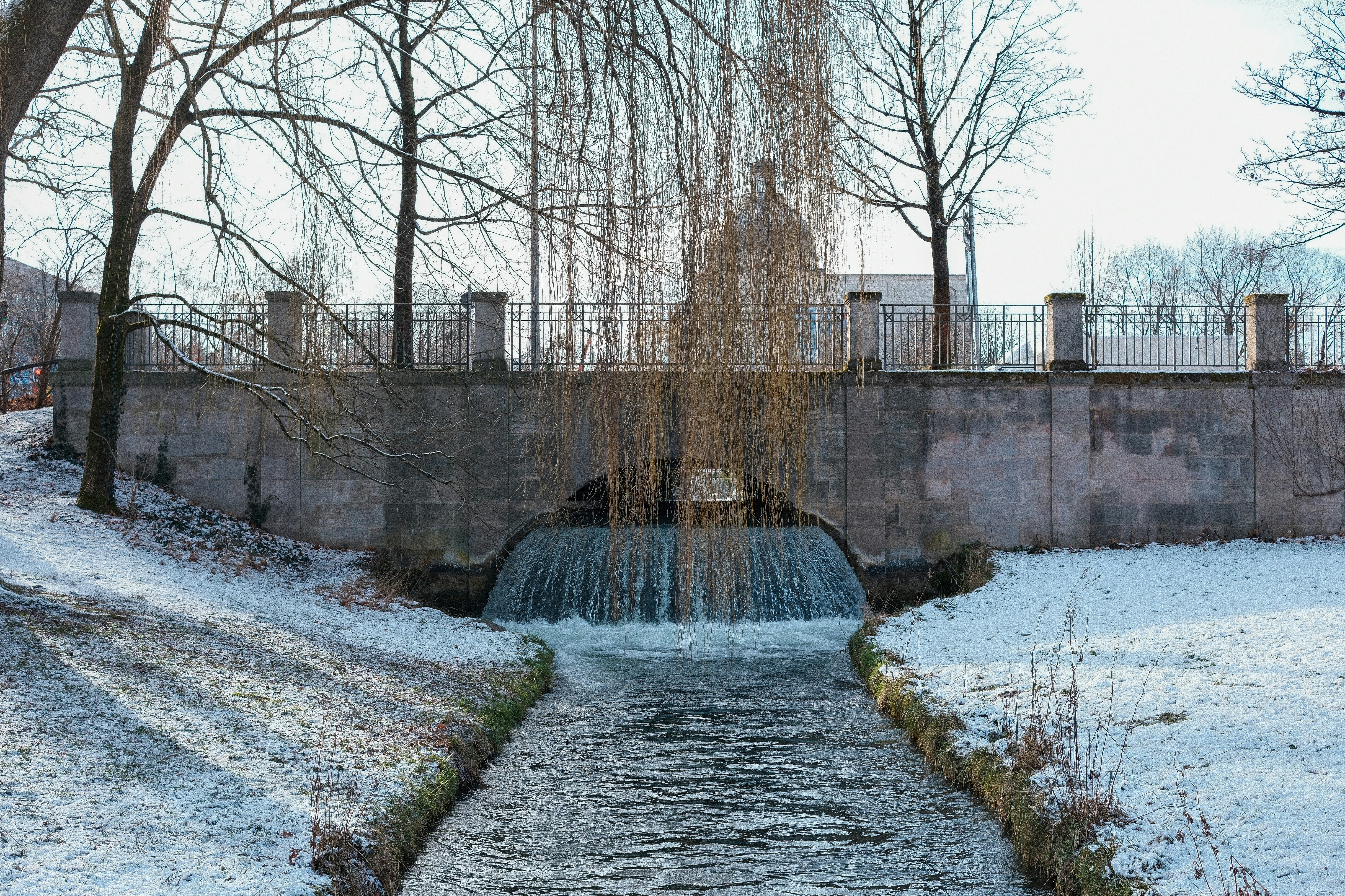 A water fountain surrounded by snow and trees