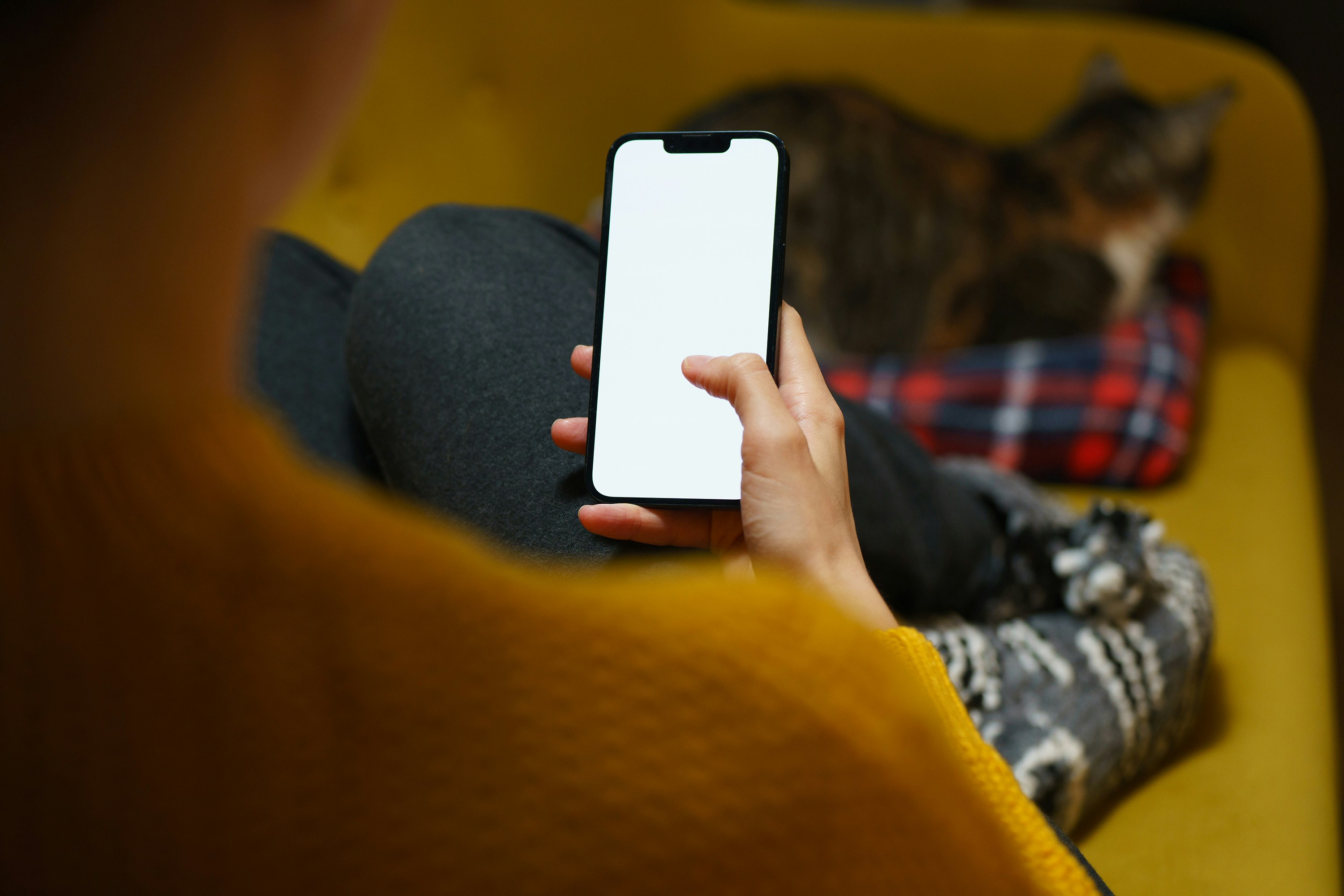 Eine Person, die auf einer Couch sitzt und ein Handy in der Hand hält