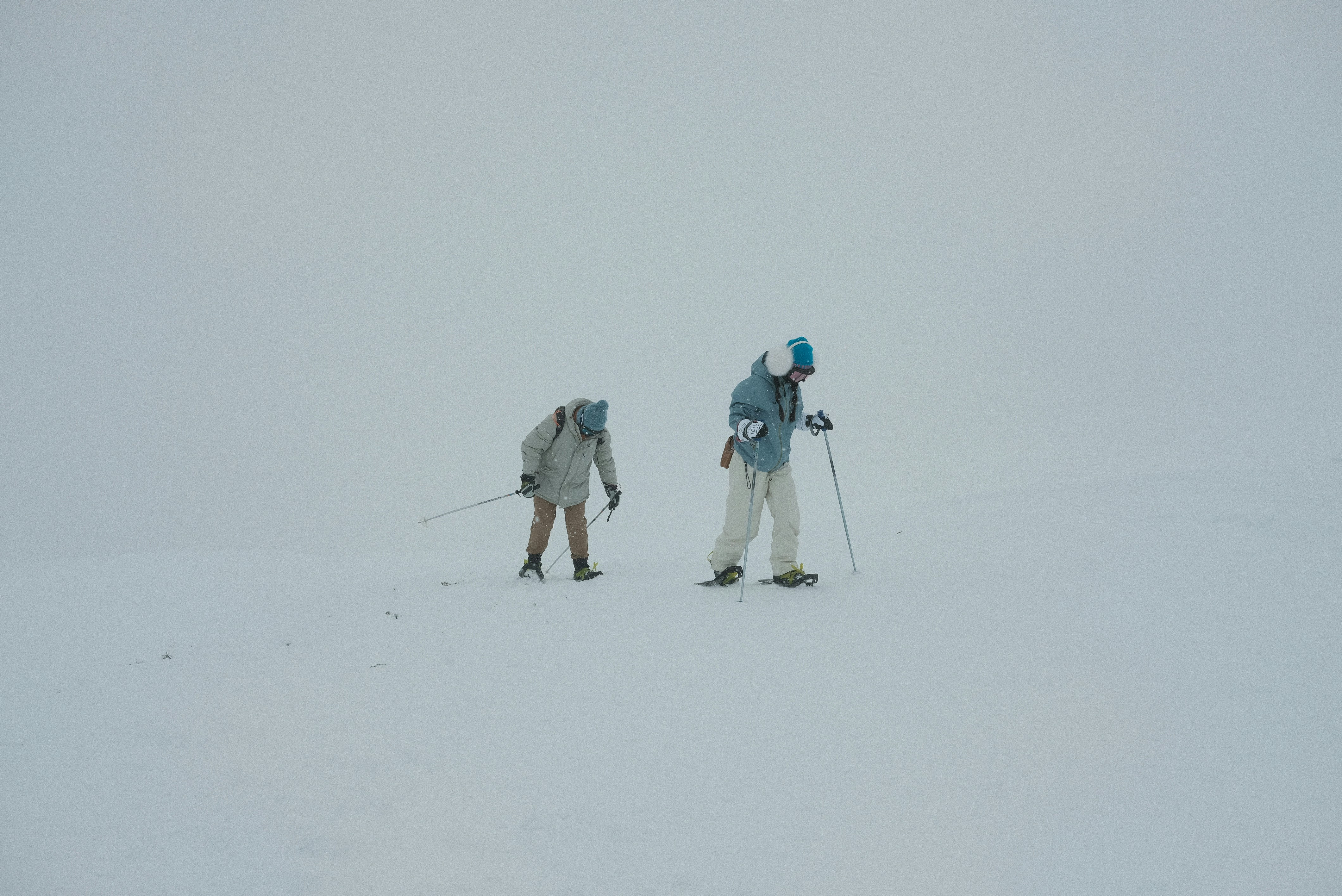 A couple of people riding skis across a snow covered slope