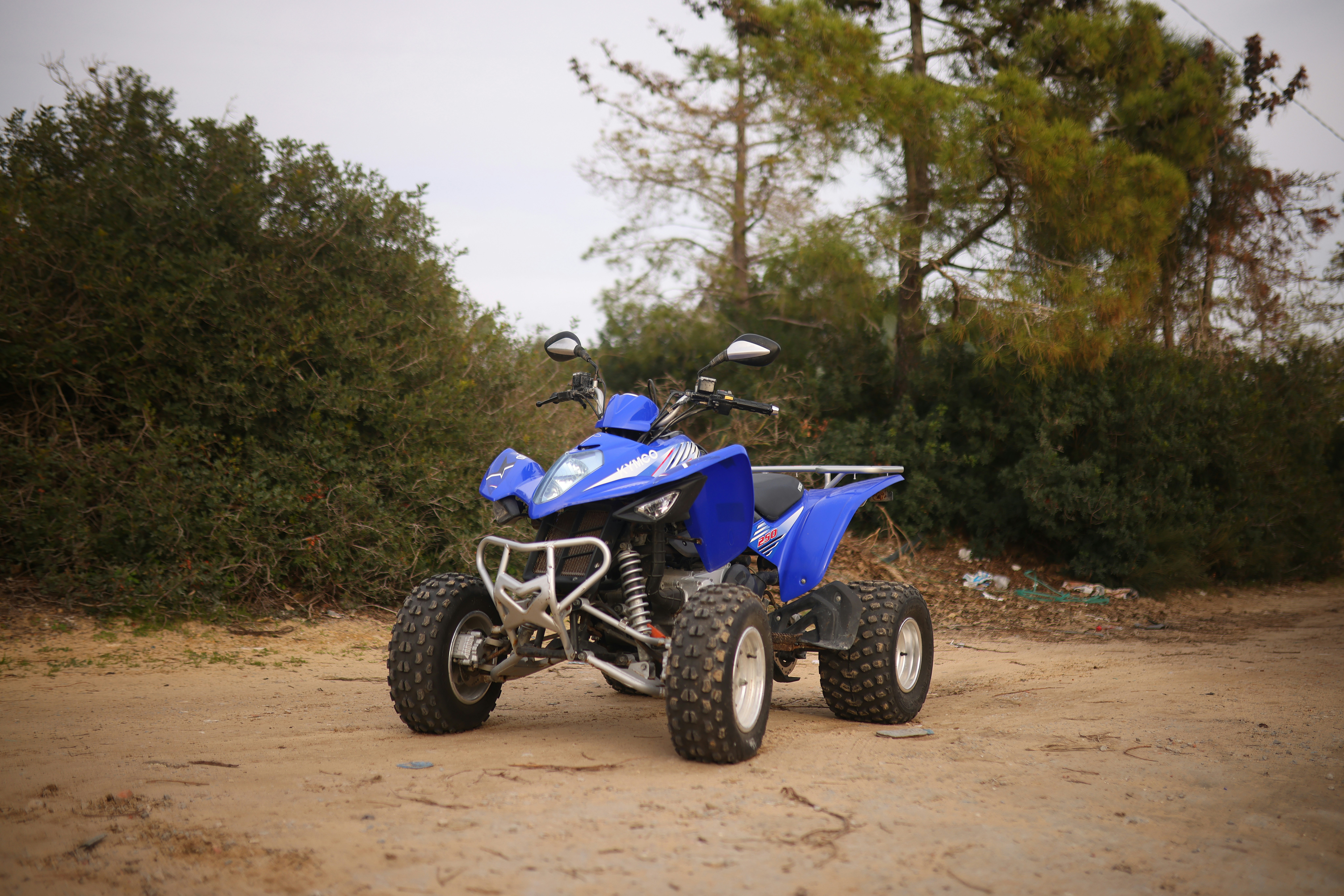 A blue four - wheeler is parked on a dirt road