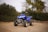 A blue four - wheeler is parked on a dirt road