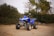 A blue four - wheeler is parked on a dirt road