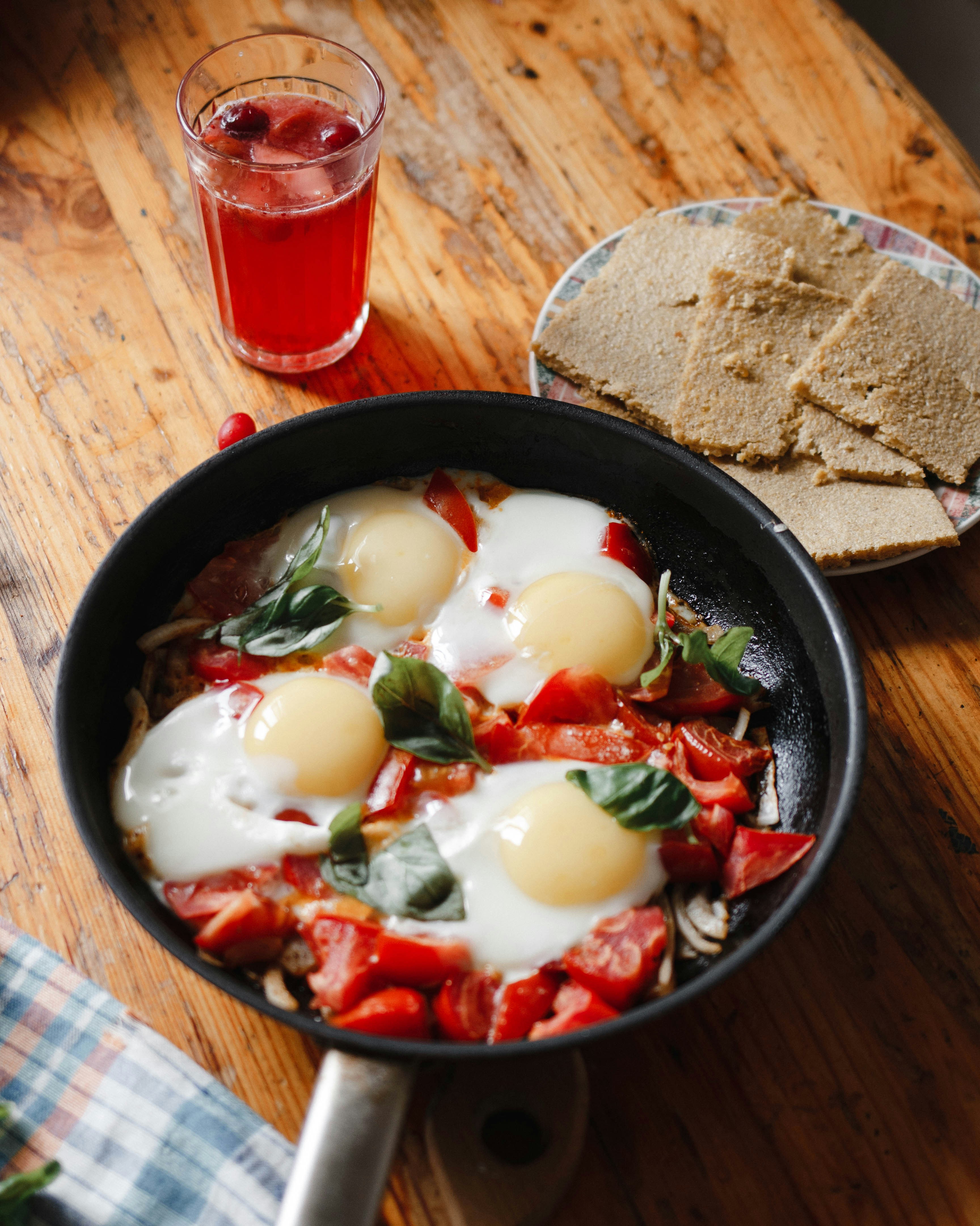 A skillet with eggs and tomatoes on a wooden table