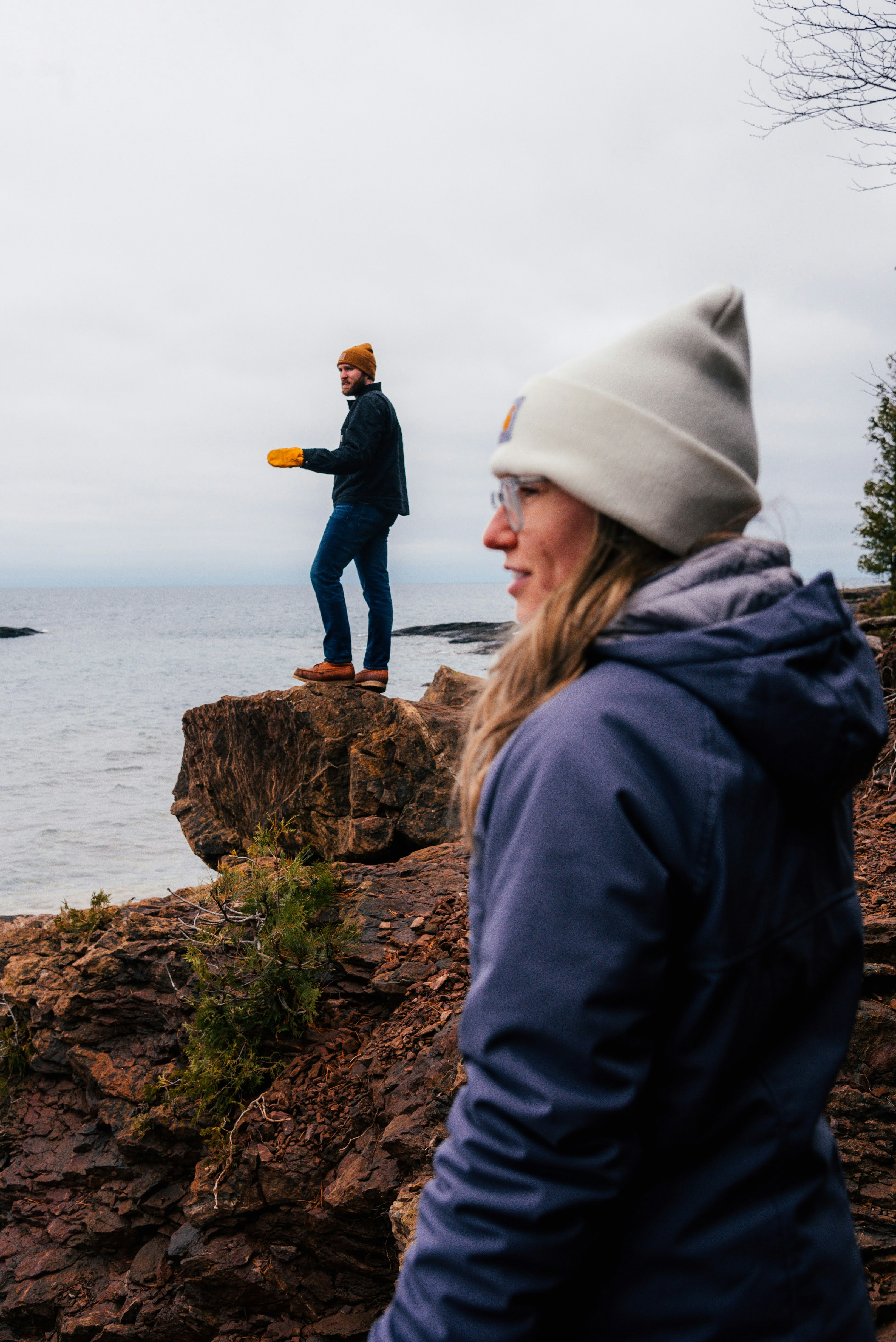 A woman standing on top of a cliff next to the ocean